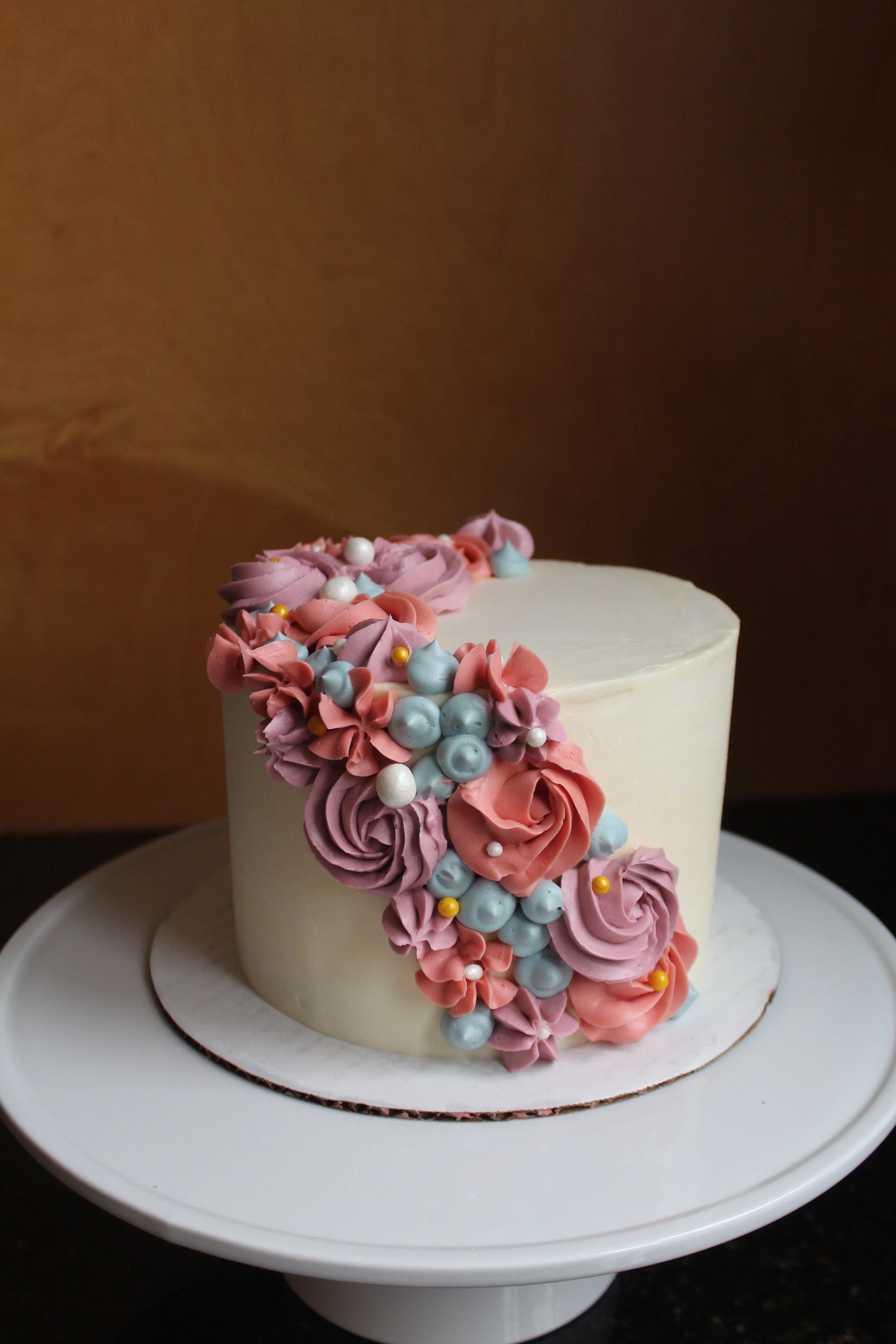White cake with abstract buttercream swirls in pink, purple, and blue.