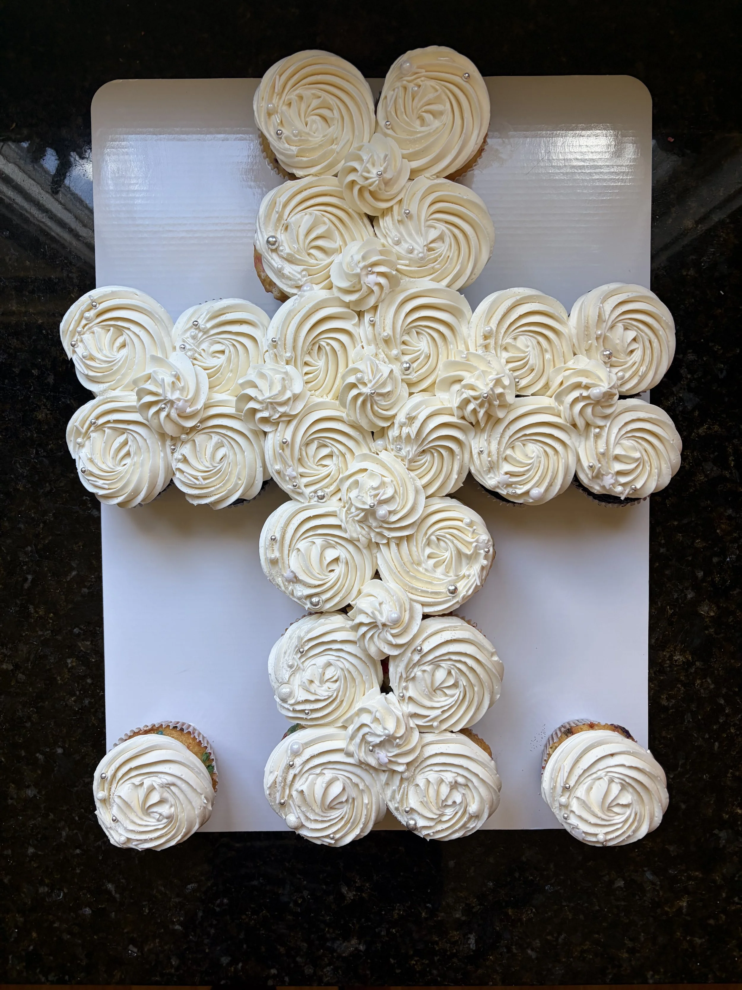 Cupcakes with vanilla frosting arranged in a cross shape