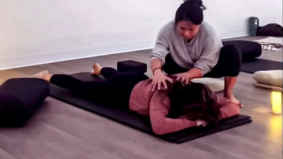 yoga teacher giving a gentle hand-on assist