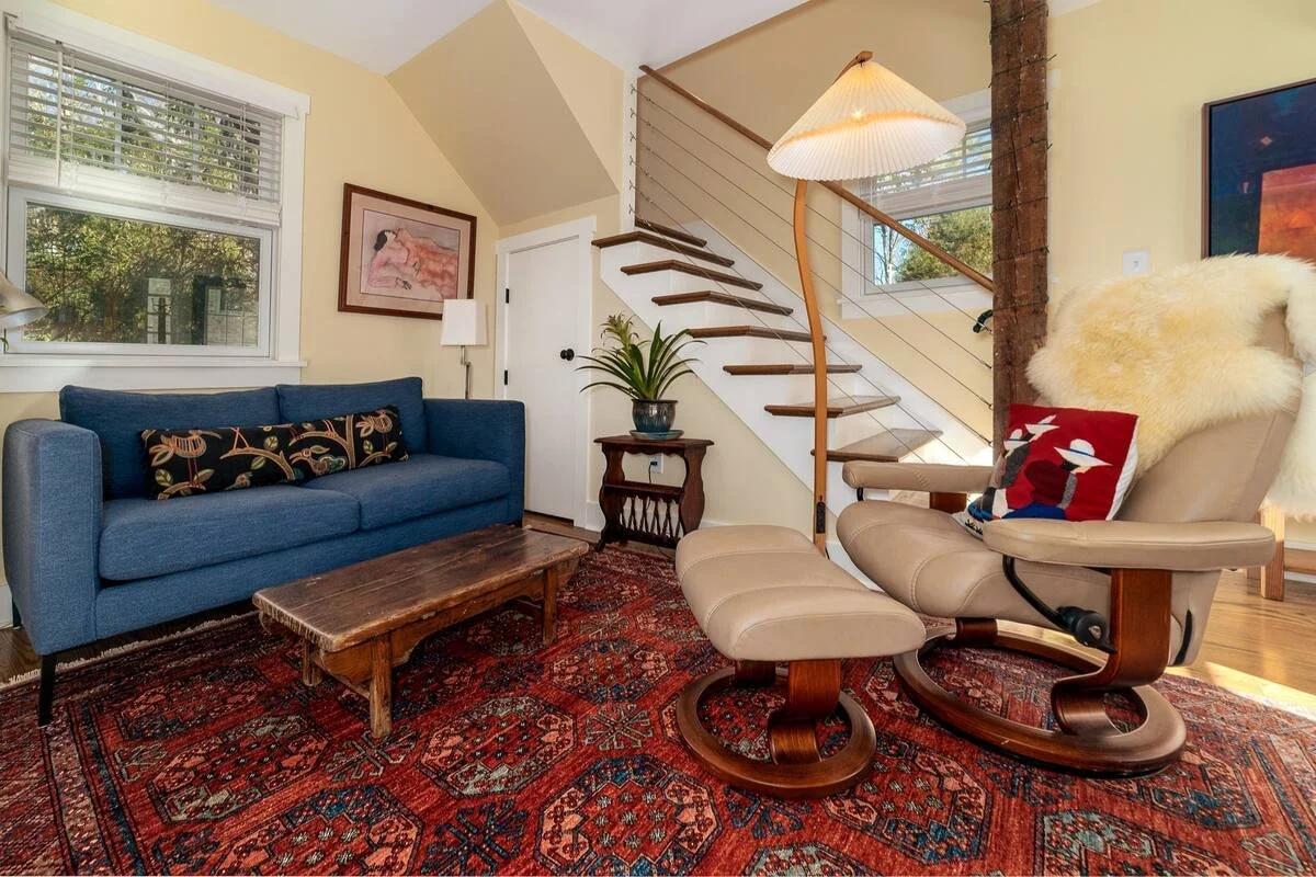 An image of a living space with a flight of stairs leading to the new addition of a second floor
