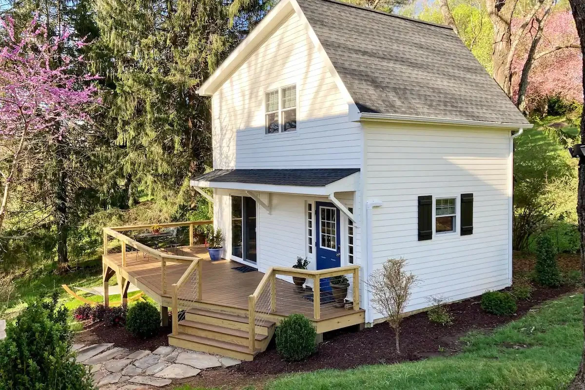 An image of a small white home with a recent addition and new deck designed by FormWright Design, Aurora McClain Architect