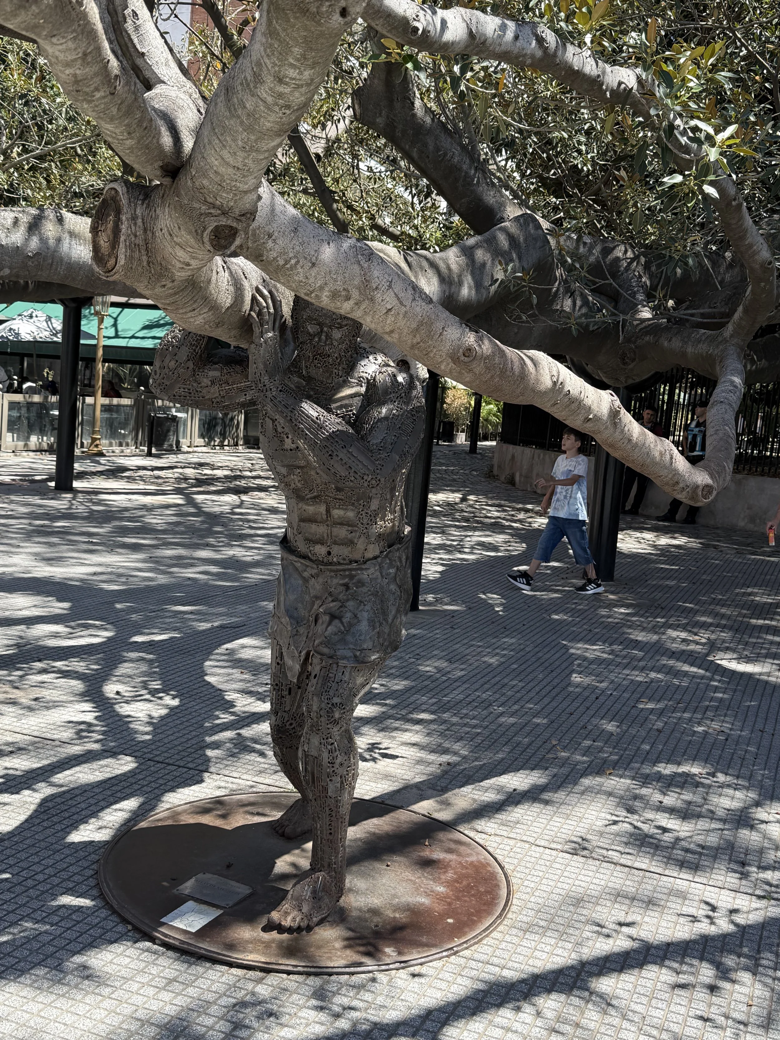 Sculpture holding up the branch of an ancient rubber tree. (tree is living)