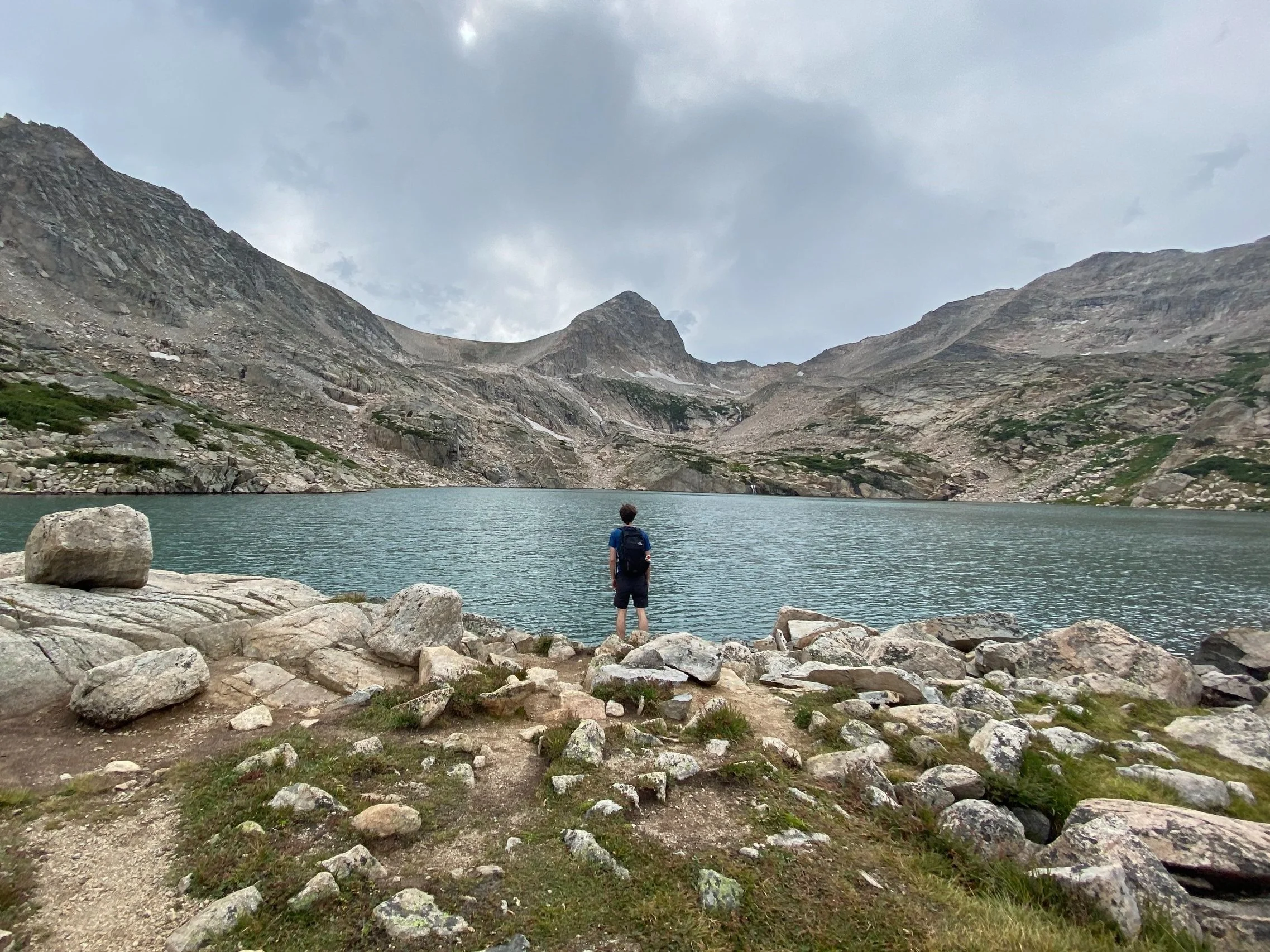 Ryyan standing and looking away from camera at the edge of Brainard lake, Colorado.