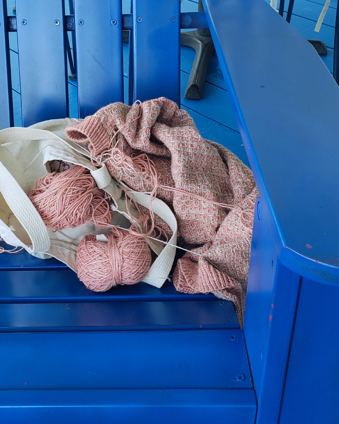 projet de tricot couleur saumon sur chaise bleue
