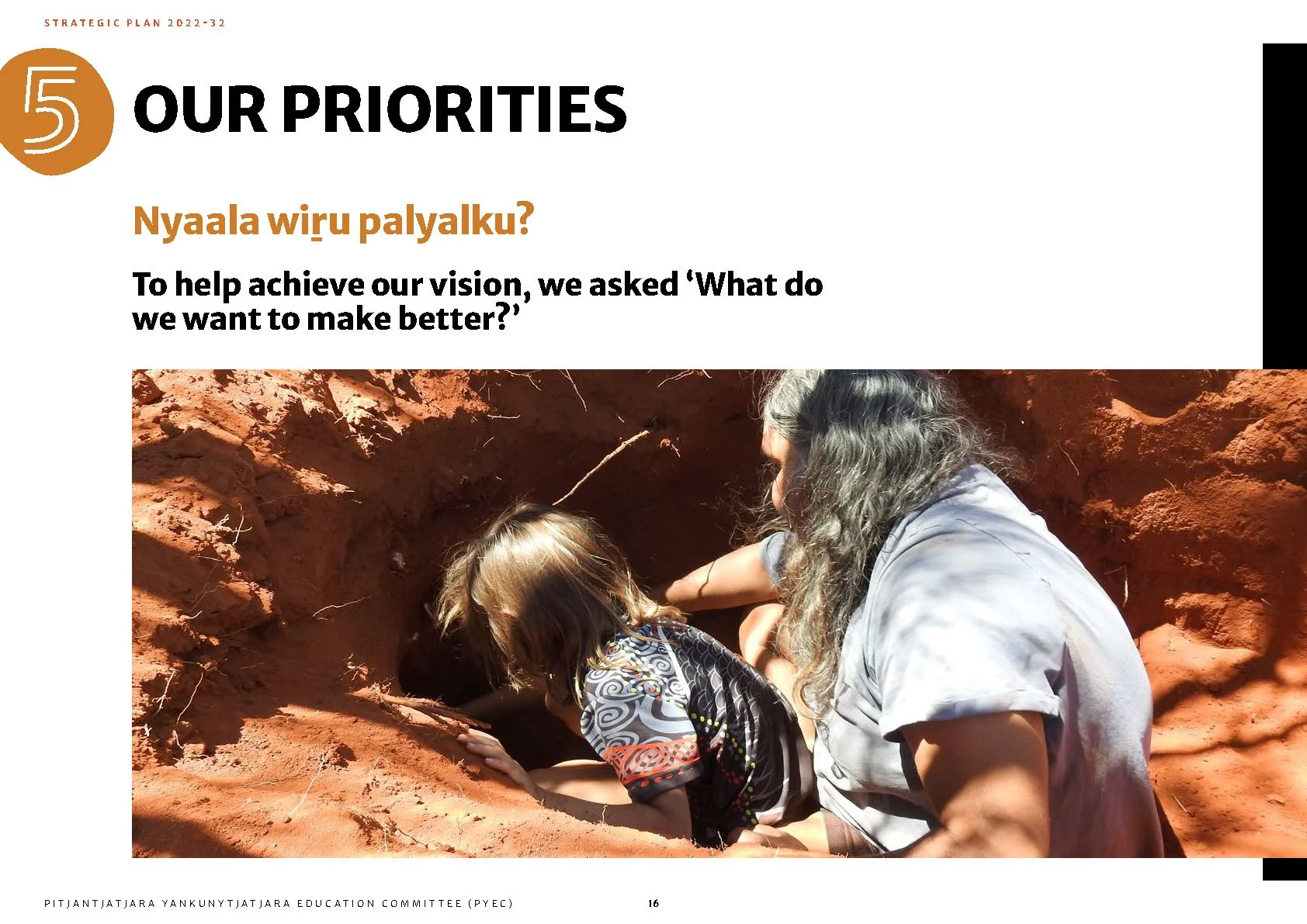 A woman and a child digging and exploring in a hole in red soil outdoors.