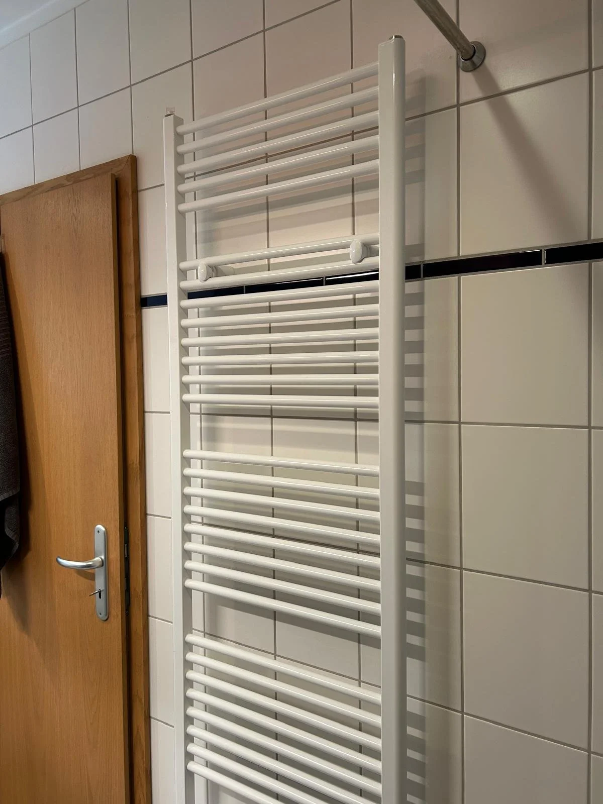 Weißer Heizkörper an einer Badezimmerwand mit weißen Fliesen Projektentwicklung Berlin