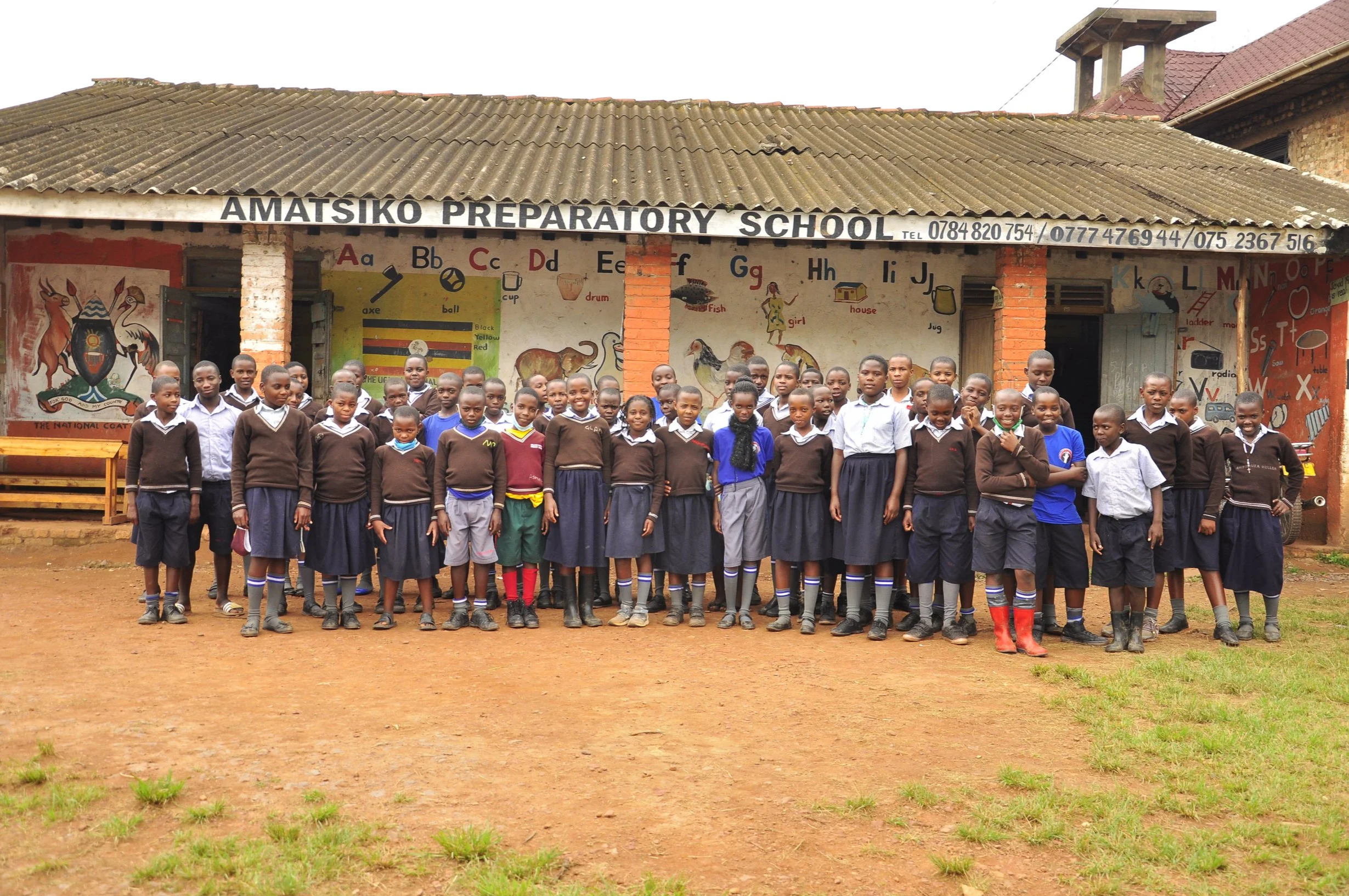 Group of children standing in front of Amatsiko Preparatory School in Uganda, representing hope, community, and access to education for vulnerable students.