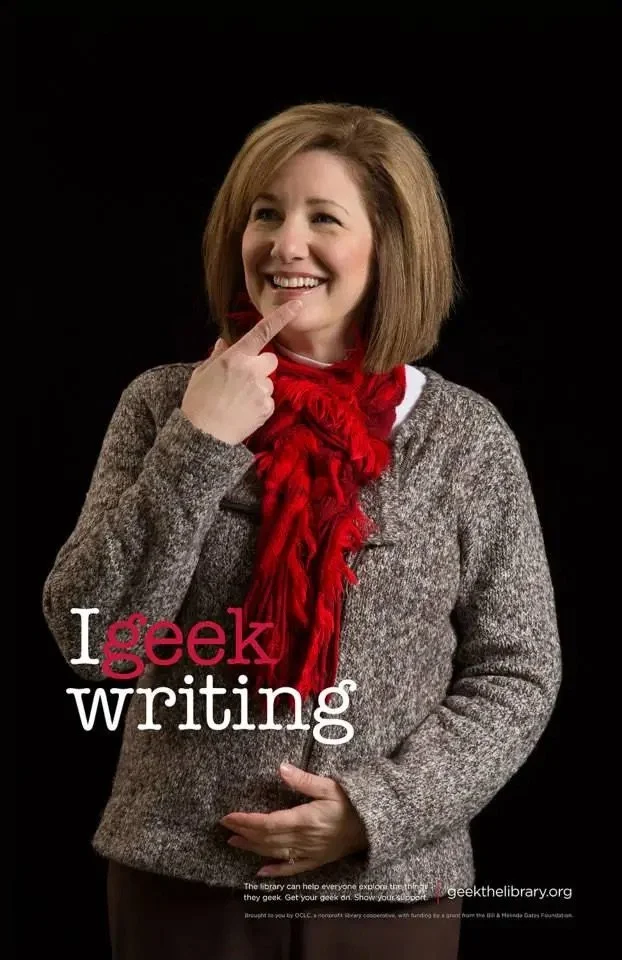 A woman smiling and touching her chin with her index finger, wearing a gray sweater and a red scarf, with the words 'I geek writing' overlayed on the image.