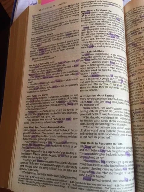 Open Bible with highlighted and underlined text, notes written in the margins, and a pink tab at the top.