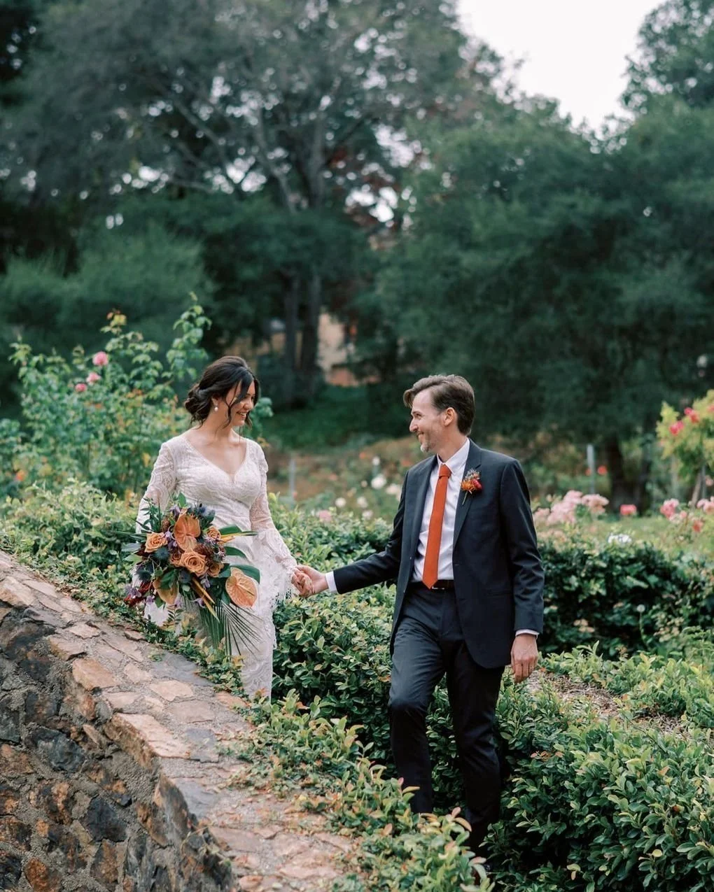 Laurie’s customers, Mariana and Carmen holding hands on a green lawn on their wedding day.