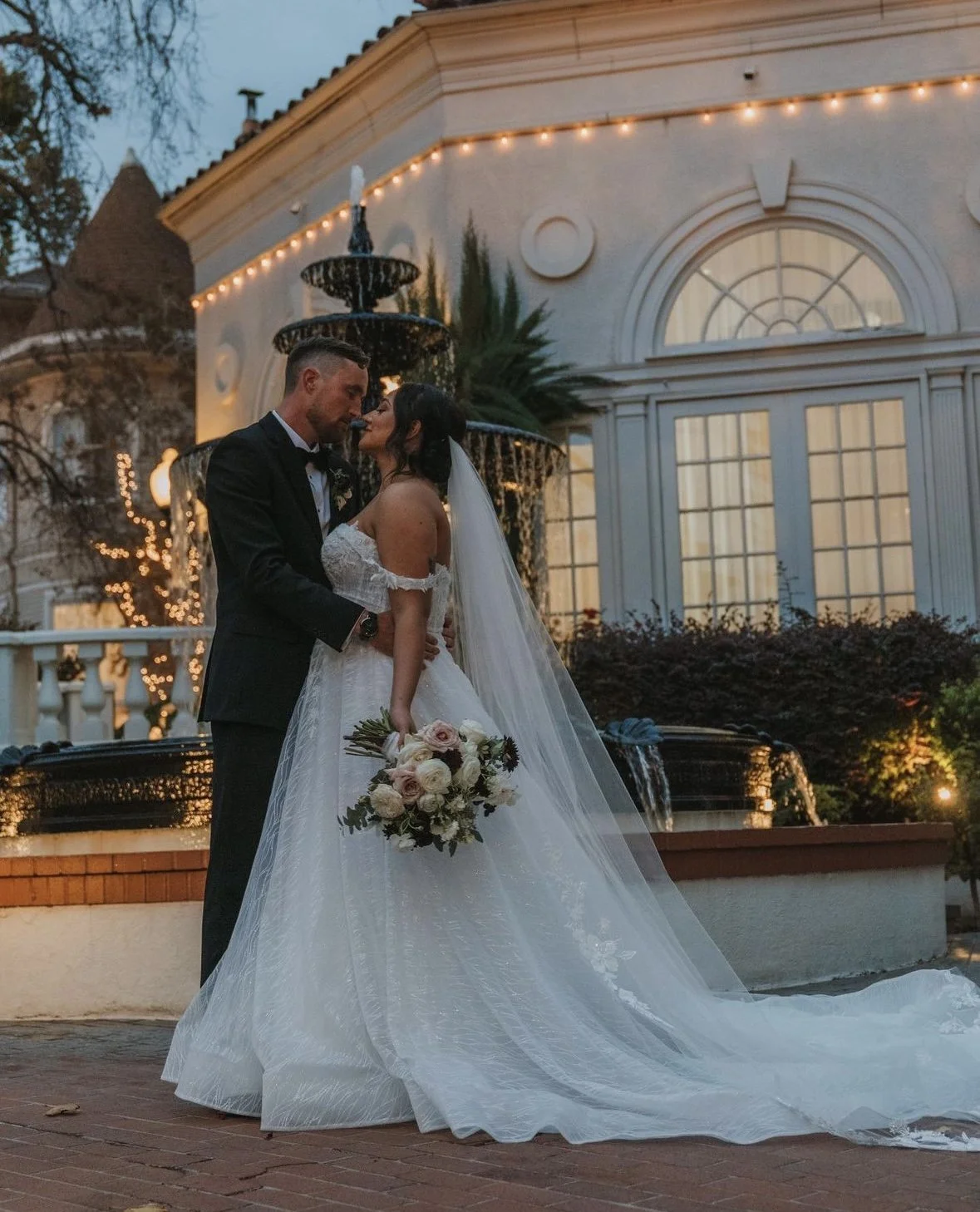 Laurie’s customers, Mariana and Carmen holding hands on a green lawn on their wedding day.