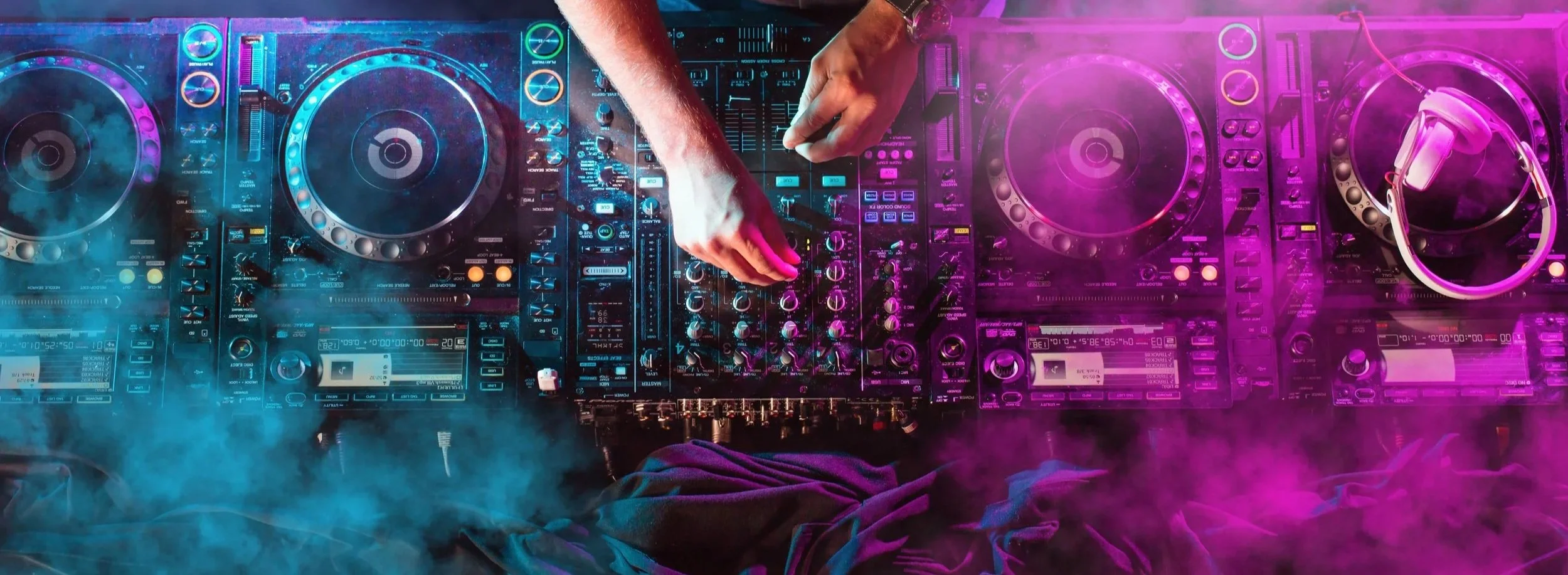 DJ mixing music with colorful neon lights and fog.