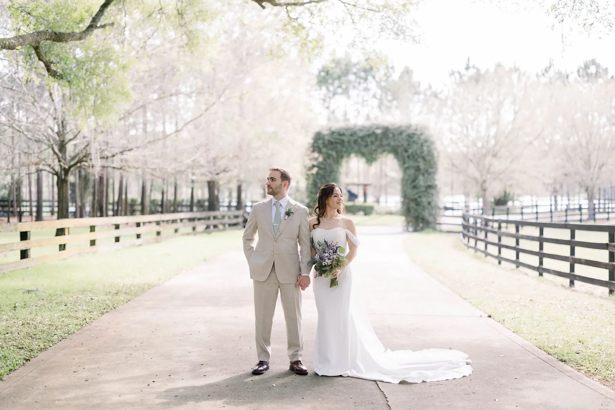 Bride and groom on the tree-lined drive with a greenery arch at Club Lake wedding venue in Apopka, Florida
