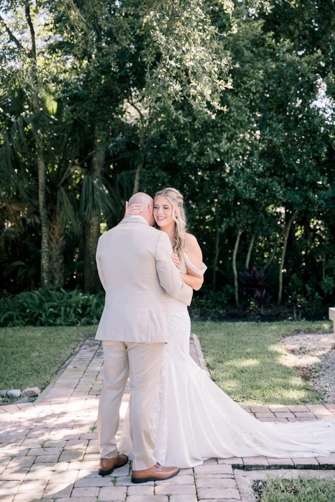 Bride and groom embrace on a garden path at The Grand 721 in New Smyrna Beach, Florida