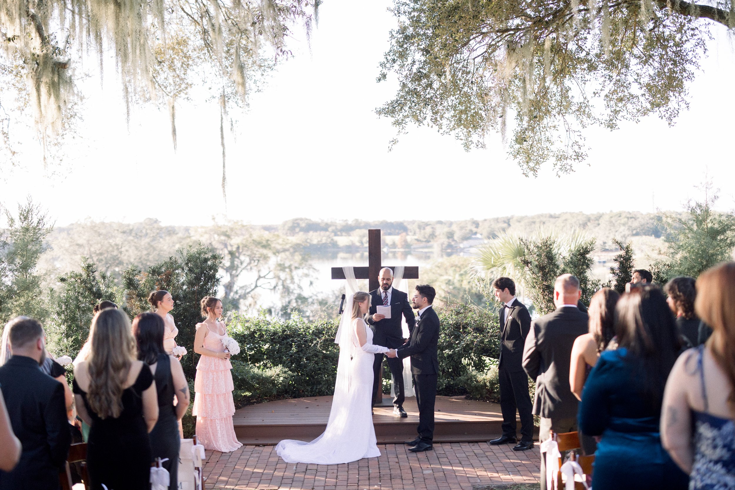 Outdoor wedding ceremony with a wooden cross overlooking the lake at Lakeview Gardens in Umatilla, Florida