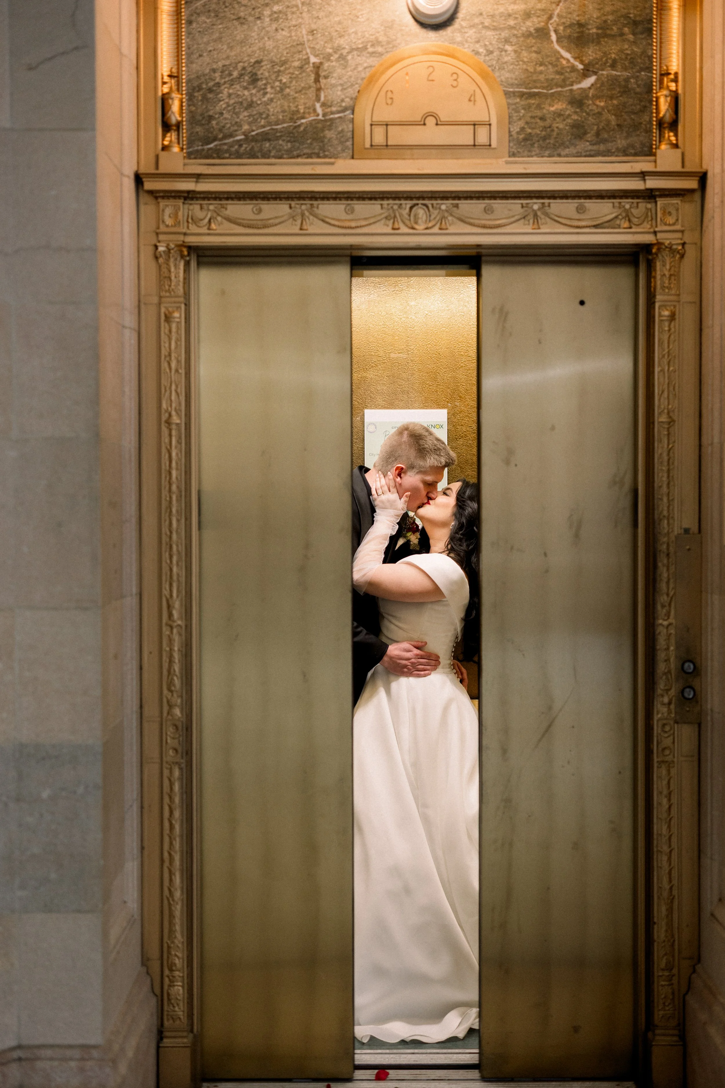 A bride and groom kissing inside an elevator.
