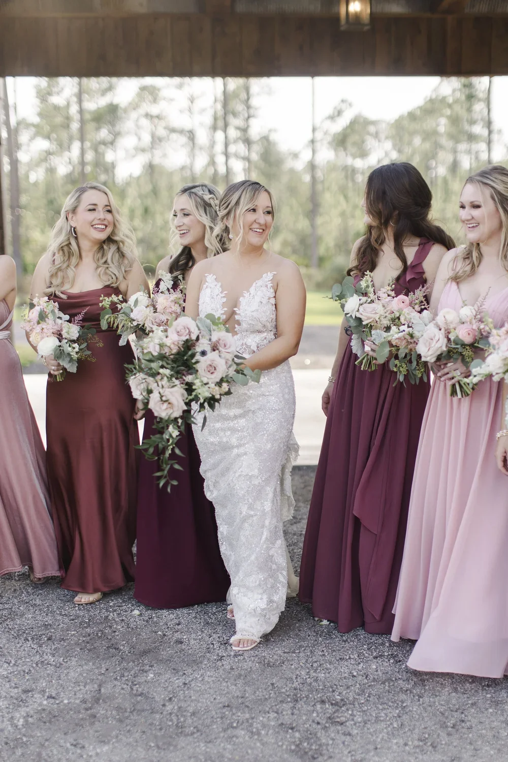 Bride laughing with her bridesmaids in burgundy and blush dresses at Granville Farms wedding venue