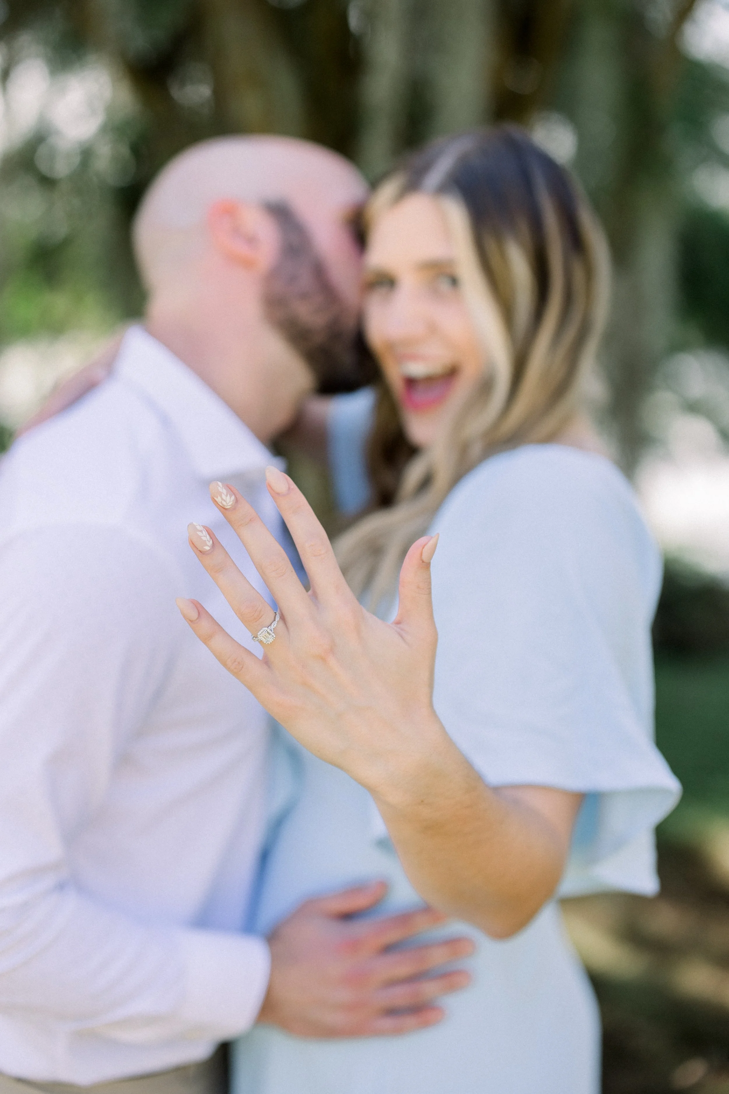 Newly engaged woman shows off her engagement ring while hugging her fiance after a surprise proposal
