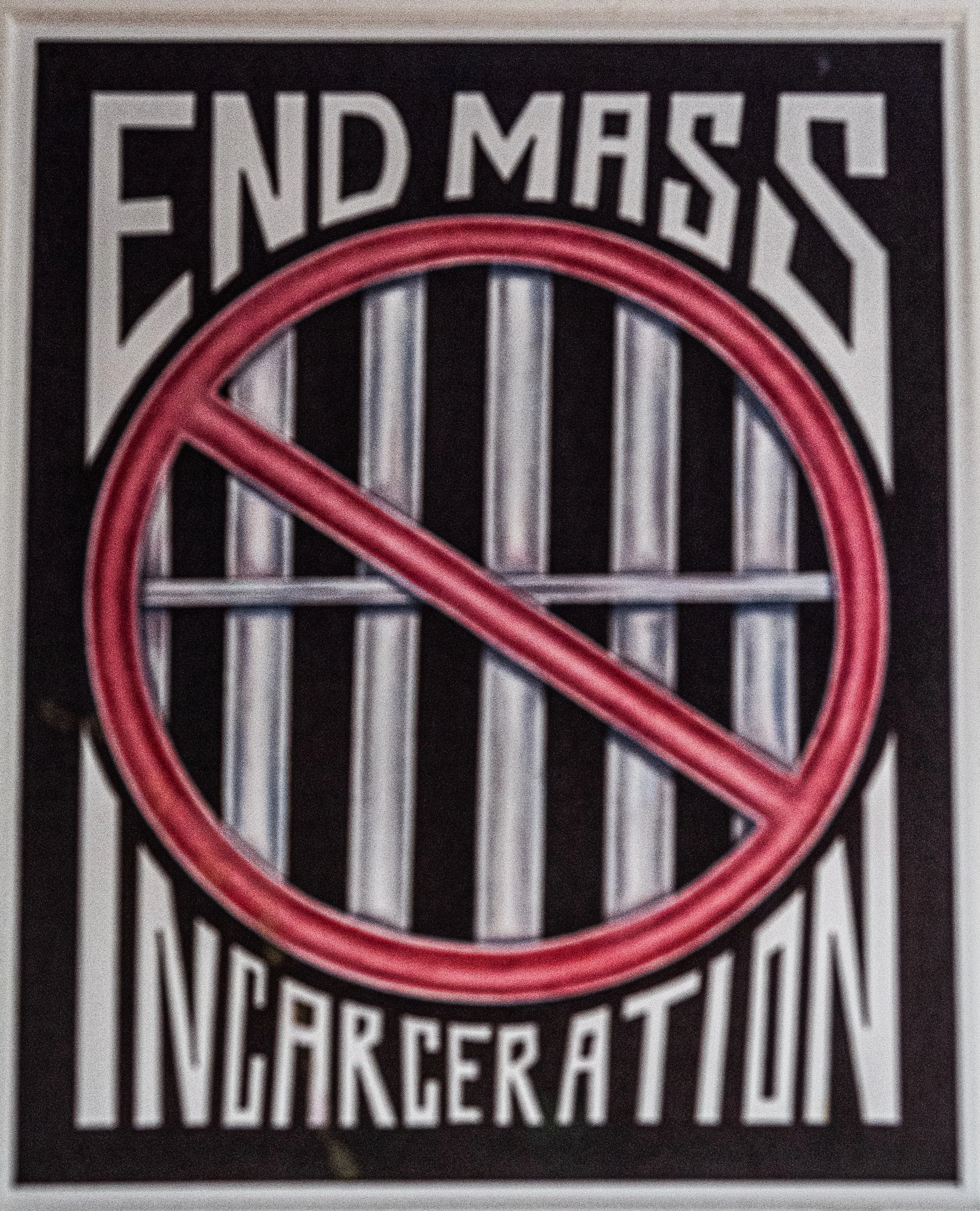 Neon sign with the words 'End Mass' in the top portion and 'Incarceration' in the bottom, with a red prohibition symbol crossed over the middle.