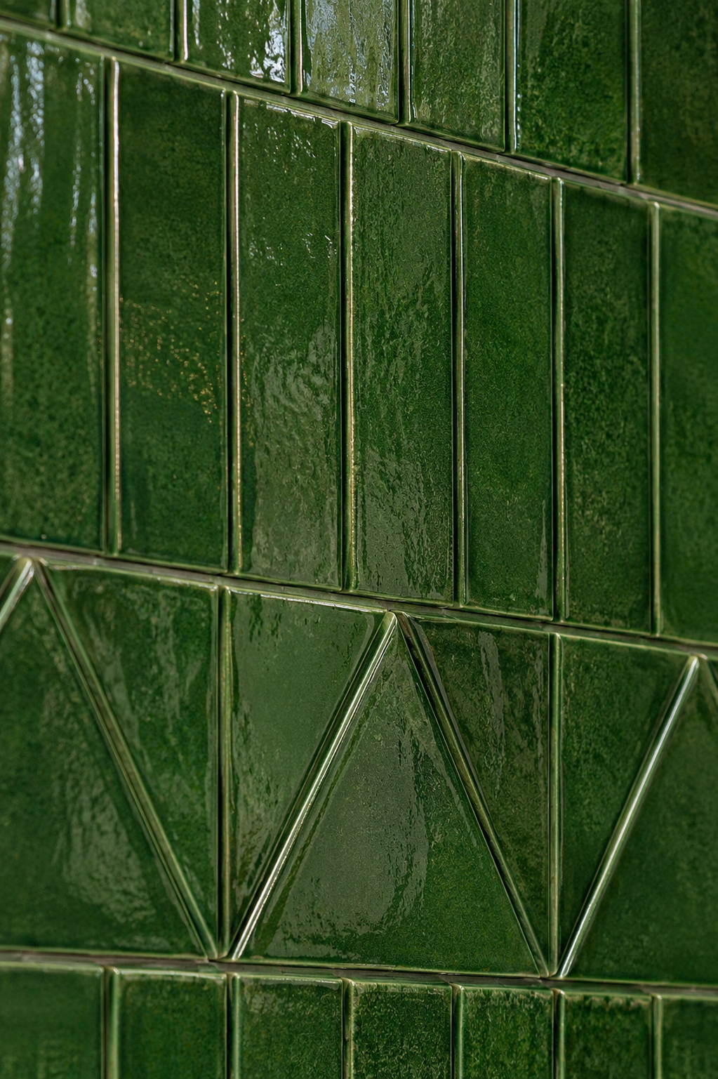 Close-up of glossy green ceramic tiles arranged in a geometric pattern on a wall.