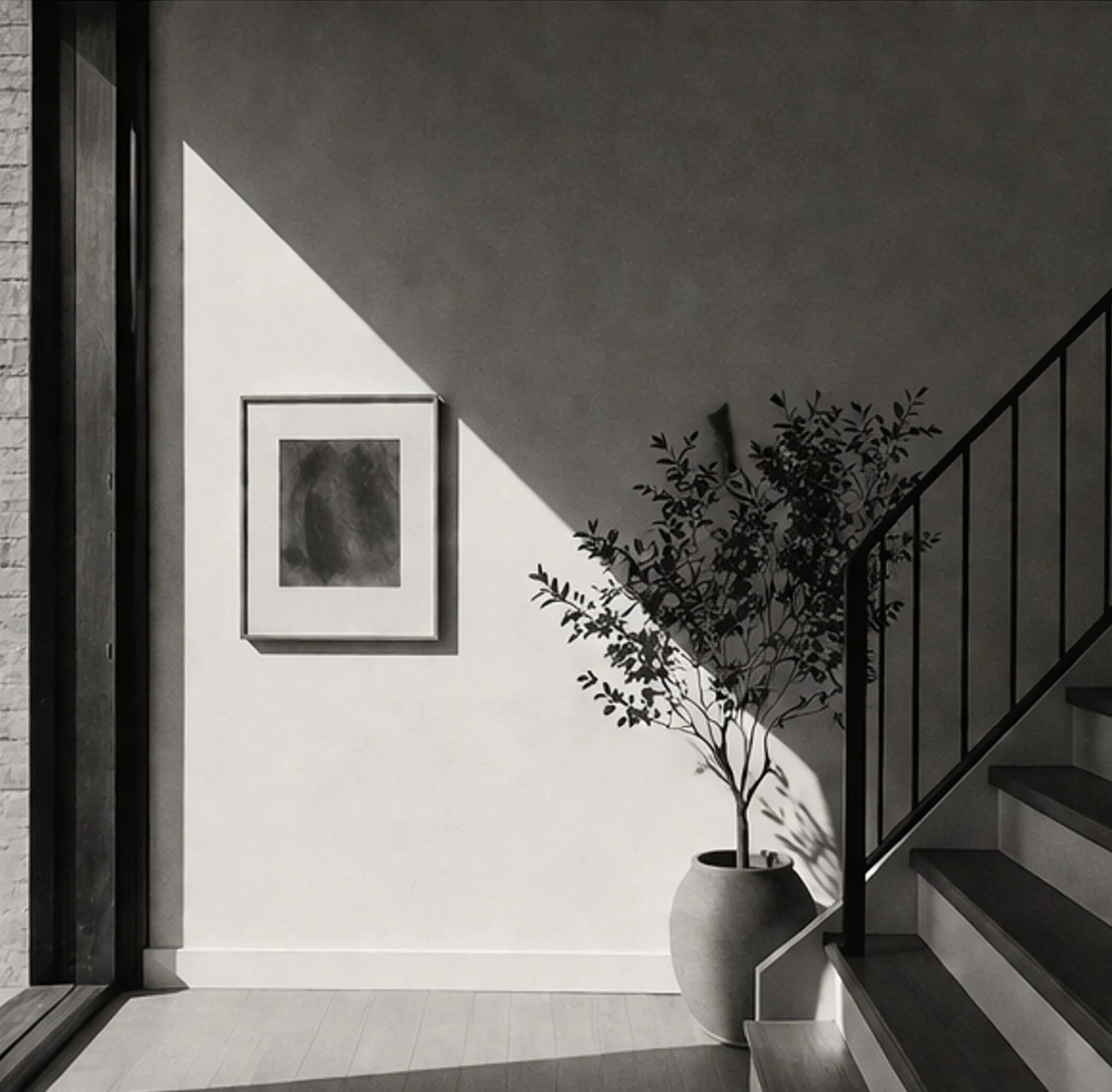 A minimalist interior scene with a staircase on the right, a potted plant casting a shadow on the wall, framed art on the wall, and a window on the left with natural light illuminating the space.