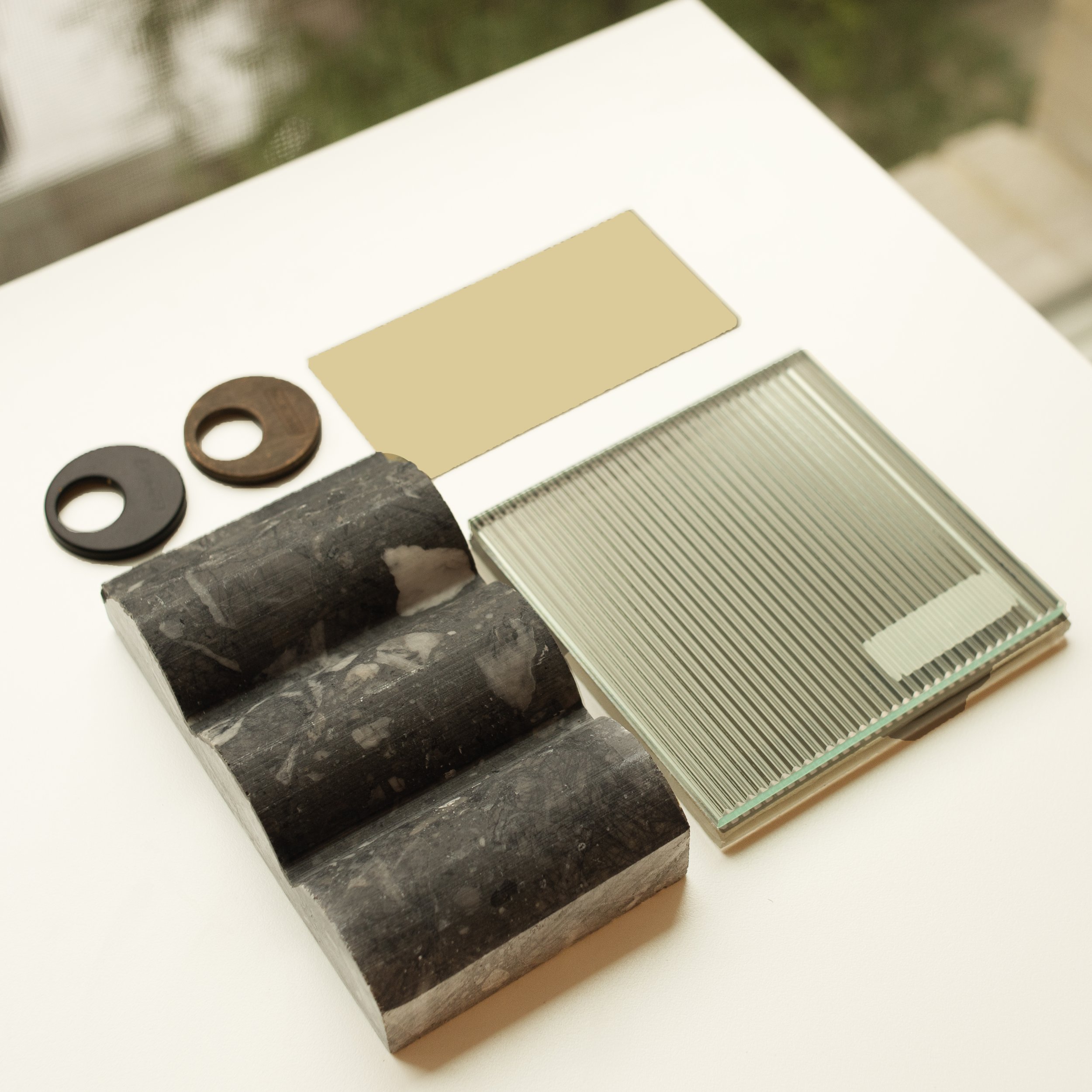 Close-up view of three stacked building material samples, including marble and granite, with circular washers on a white surface.