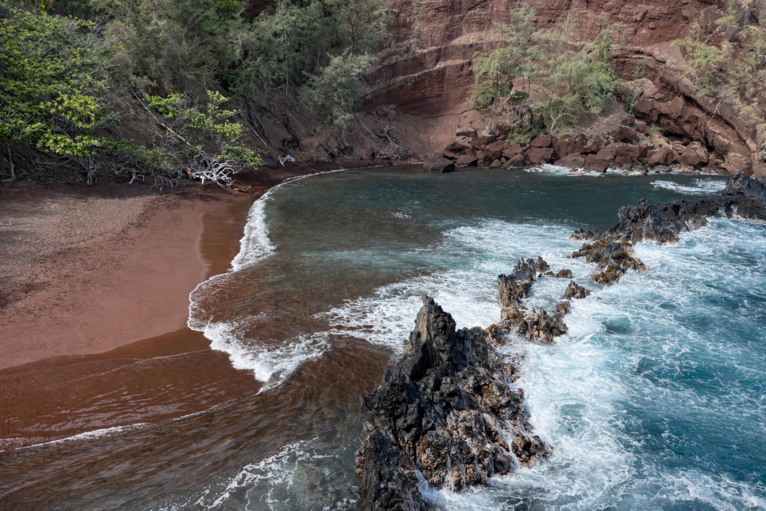 Red sand beach forming a natural cove used as a visual metaphor for resilience and capacity