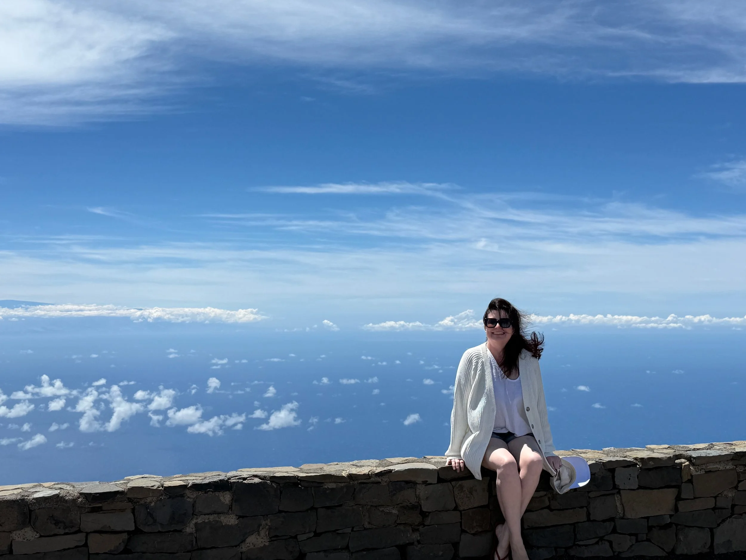 Person sitting above the clouds, symbolizing creating space, clarity, and perspective.