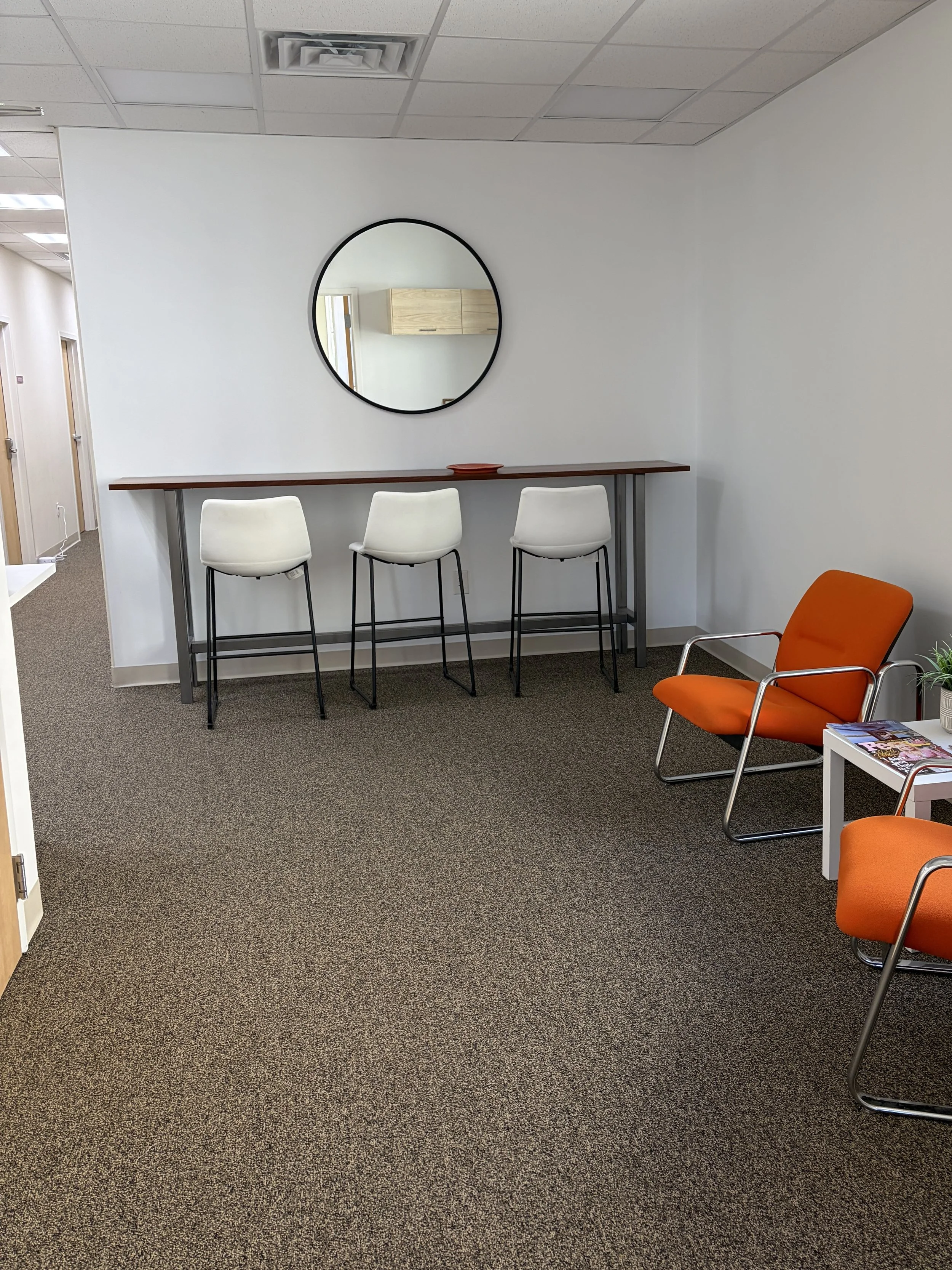 Therapist in Melrose office waiting area with orange chairs and table