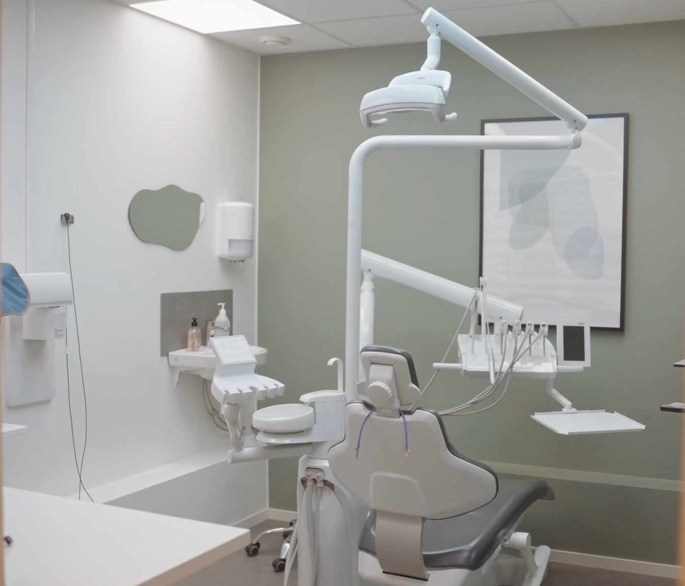 A dental examination room with dental chair, overhead light, and dental equipment.