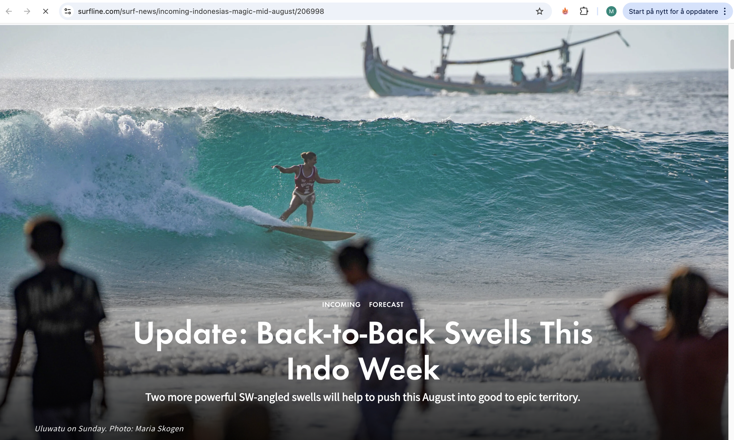 A surfer riding a large wave with a boat in the background, and people watching on the beach in the foreground.