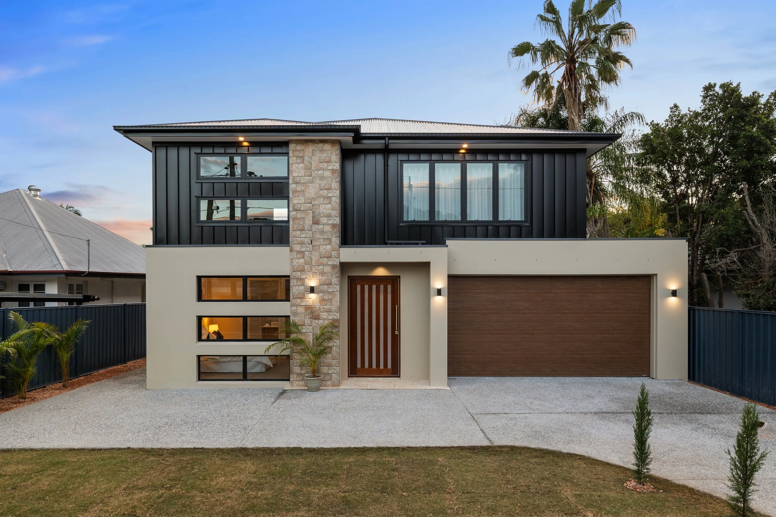 Modern luxury home shot in dusk with black weatherboard and luxury stone located in Brisbane City.