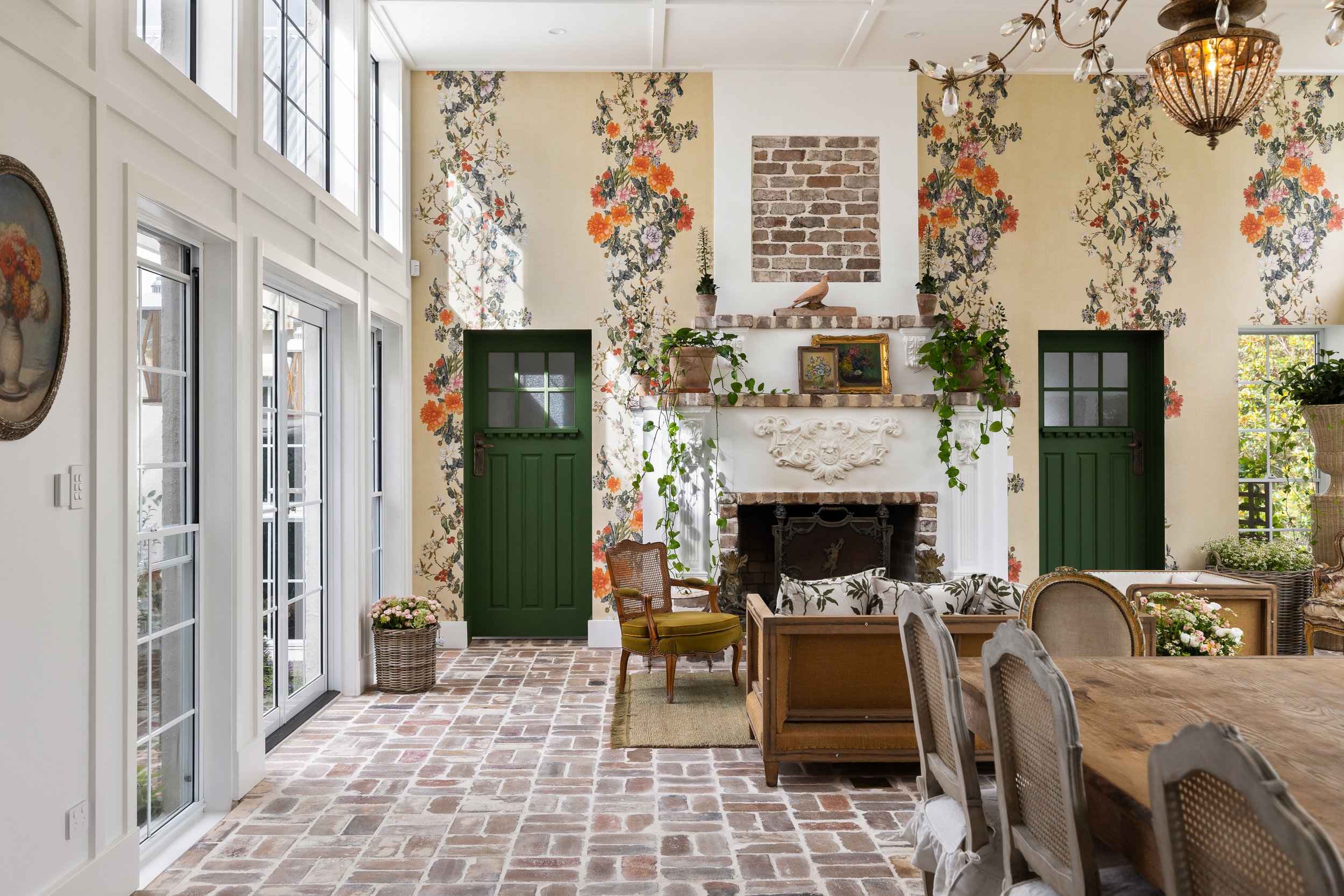 Sunlight glass living room with floral wallpaper and green doors located in Gold Coast.