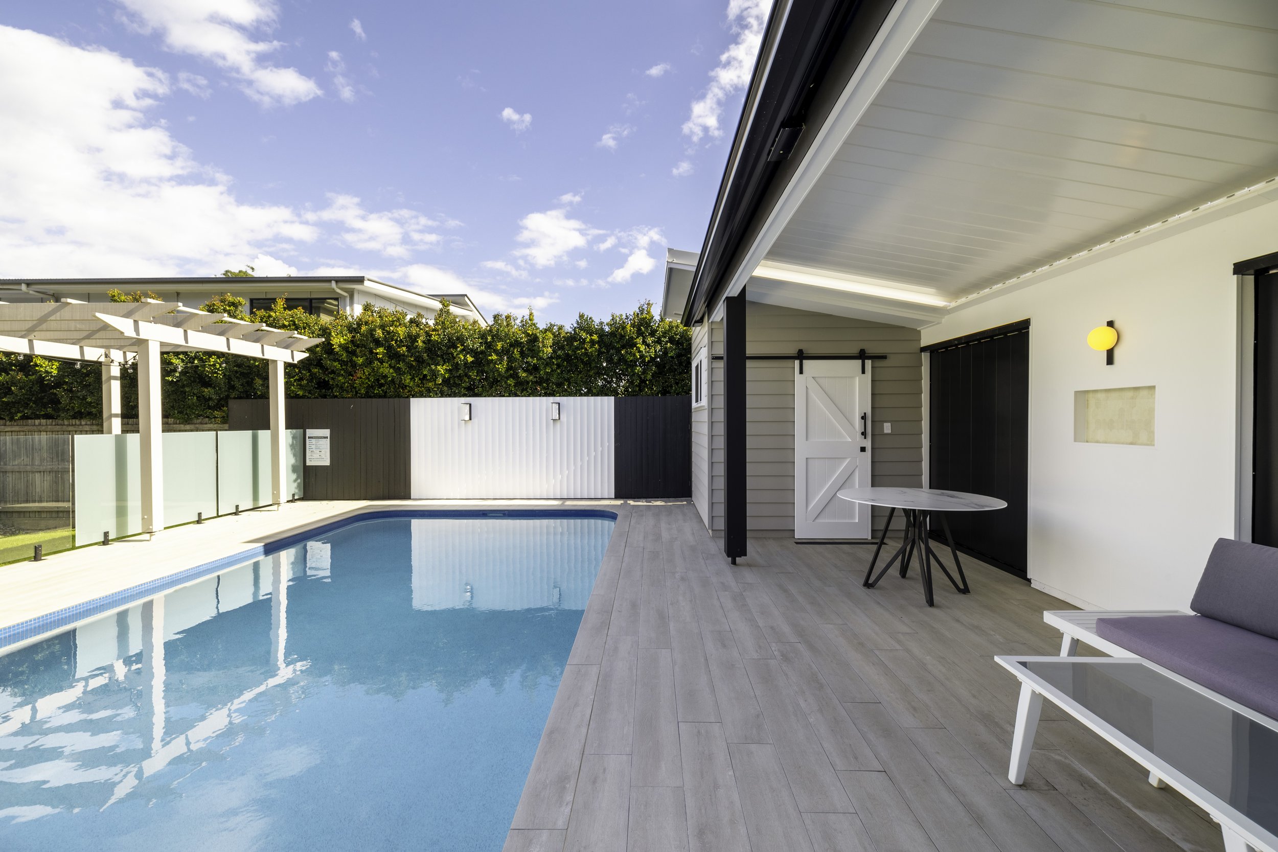 New pool house with large barn door and in-built pool with modern colours and fixtures and fitting located in Brisbane City.