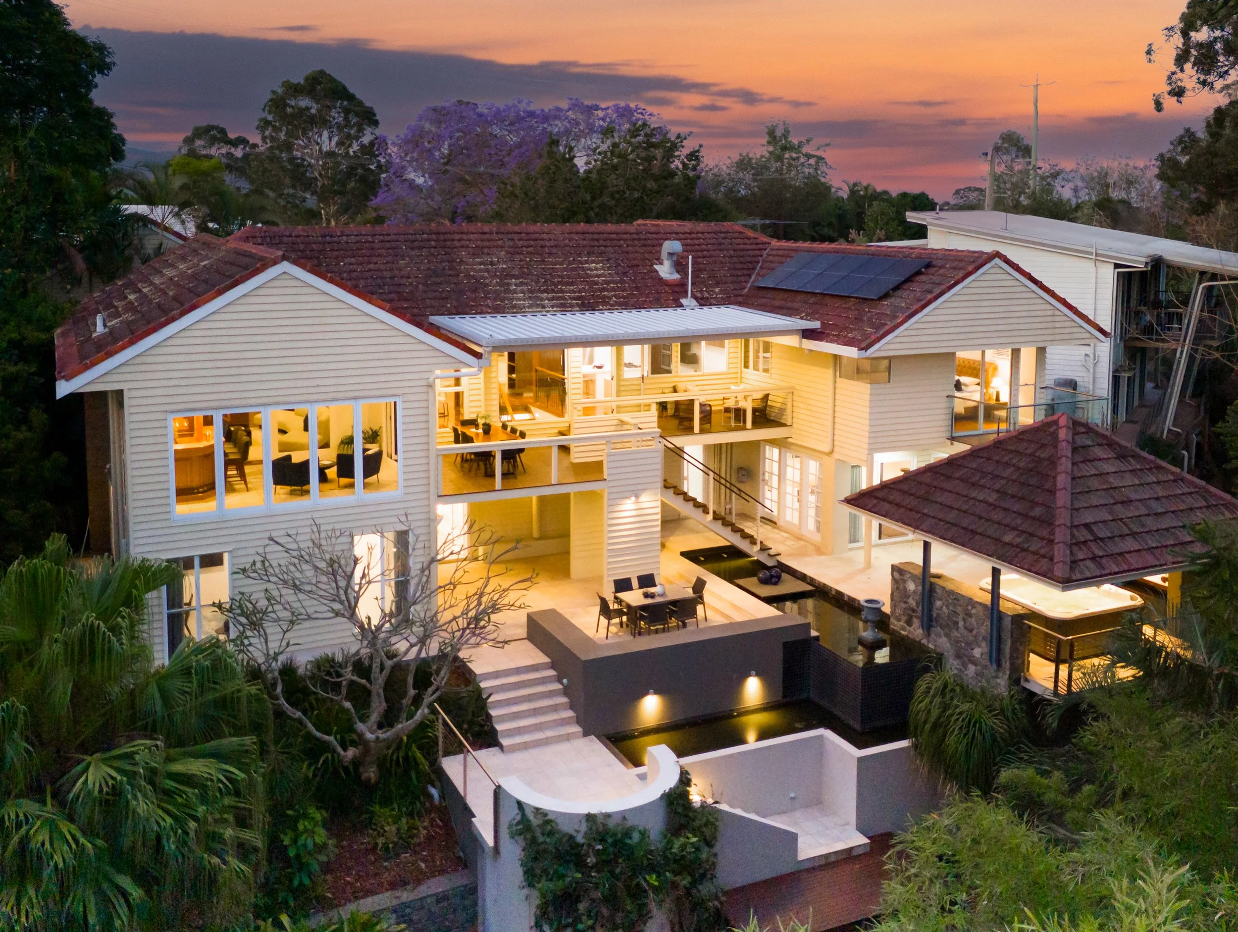 Drone shot off a historical home shot in dusk with large water features, inbuilt spar and large backyard.