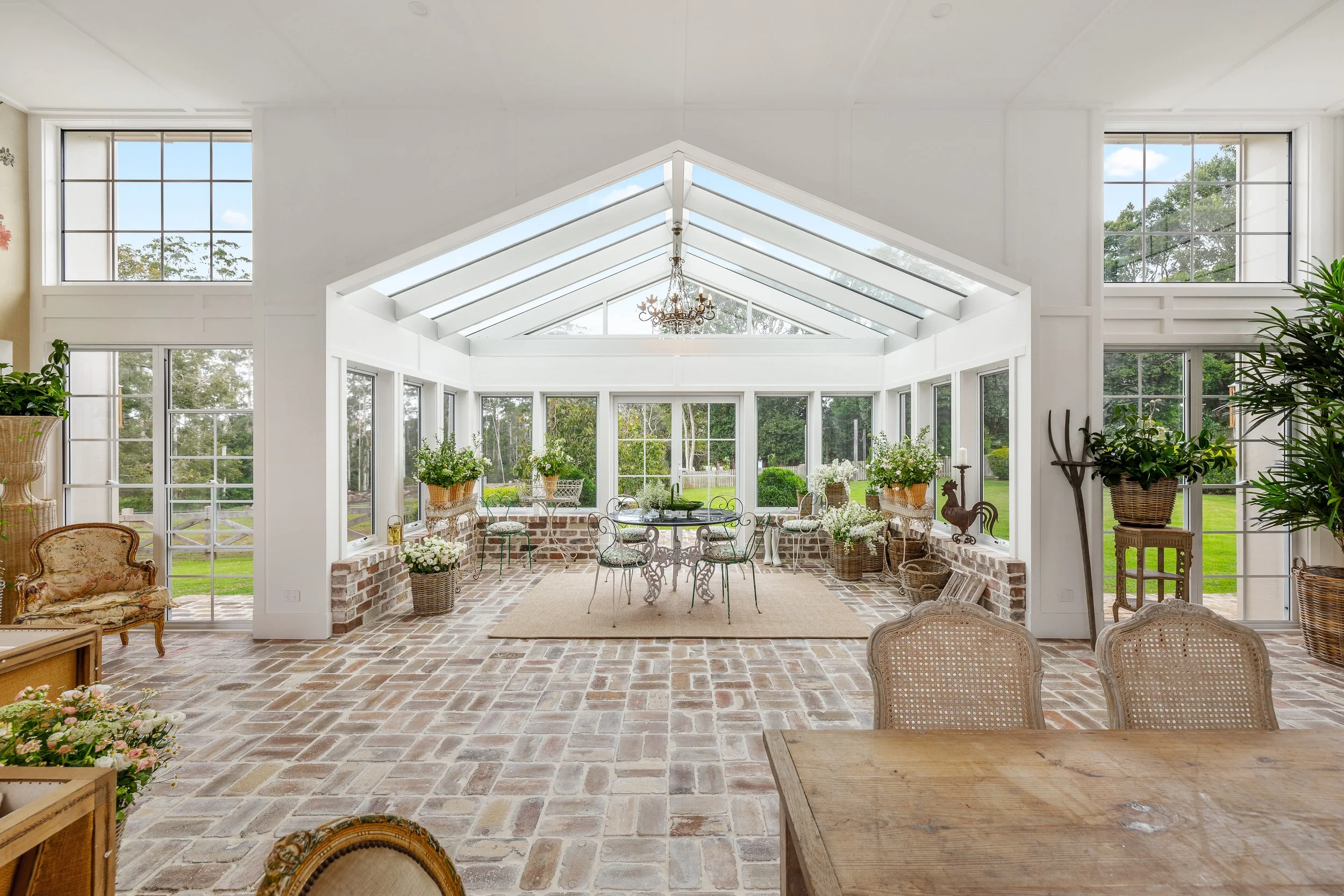 Fully glassed  living room with recycled bricks as floor and wooden furniture on a property in Gold Coast.