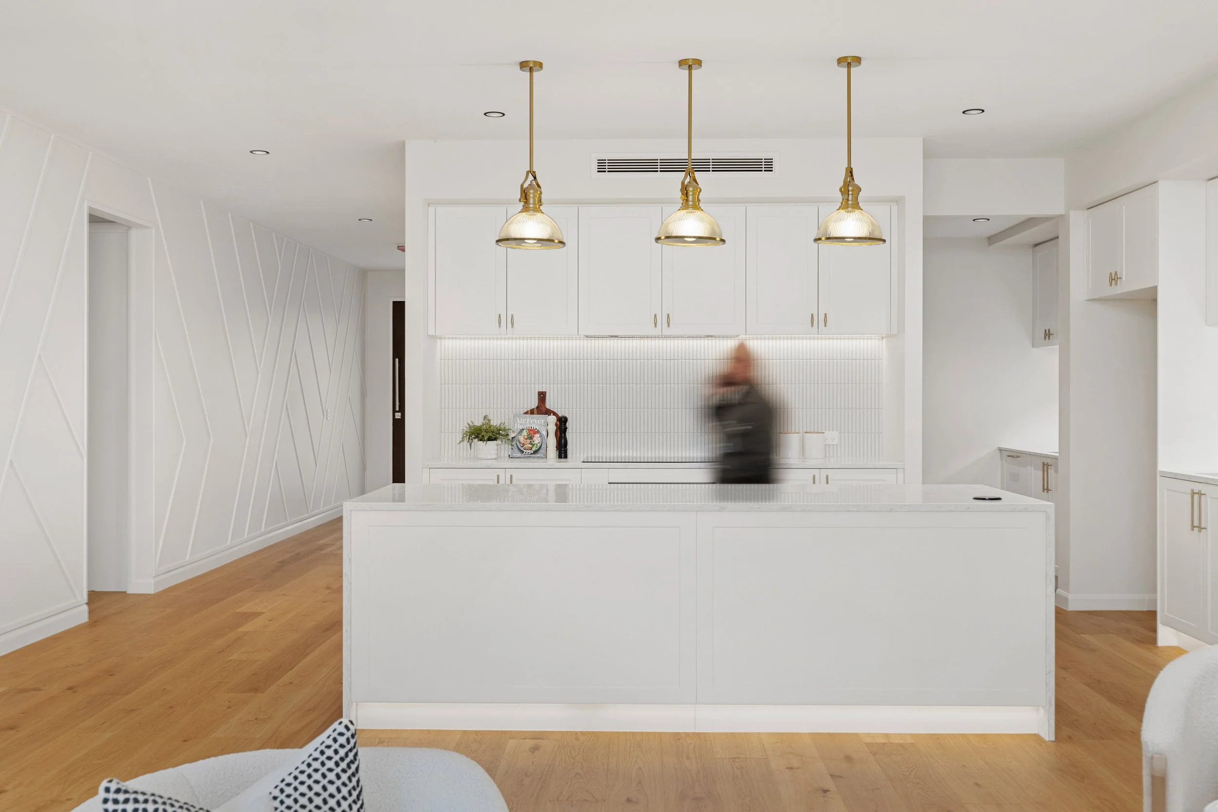 Modern kitchen with a blurry personal walking alongside the bench.