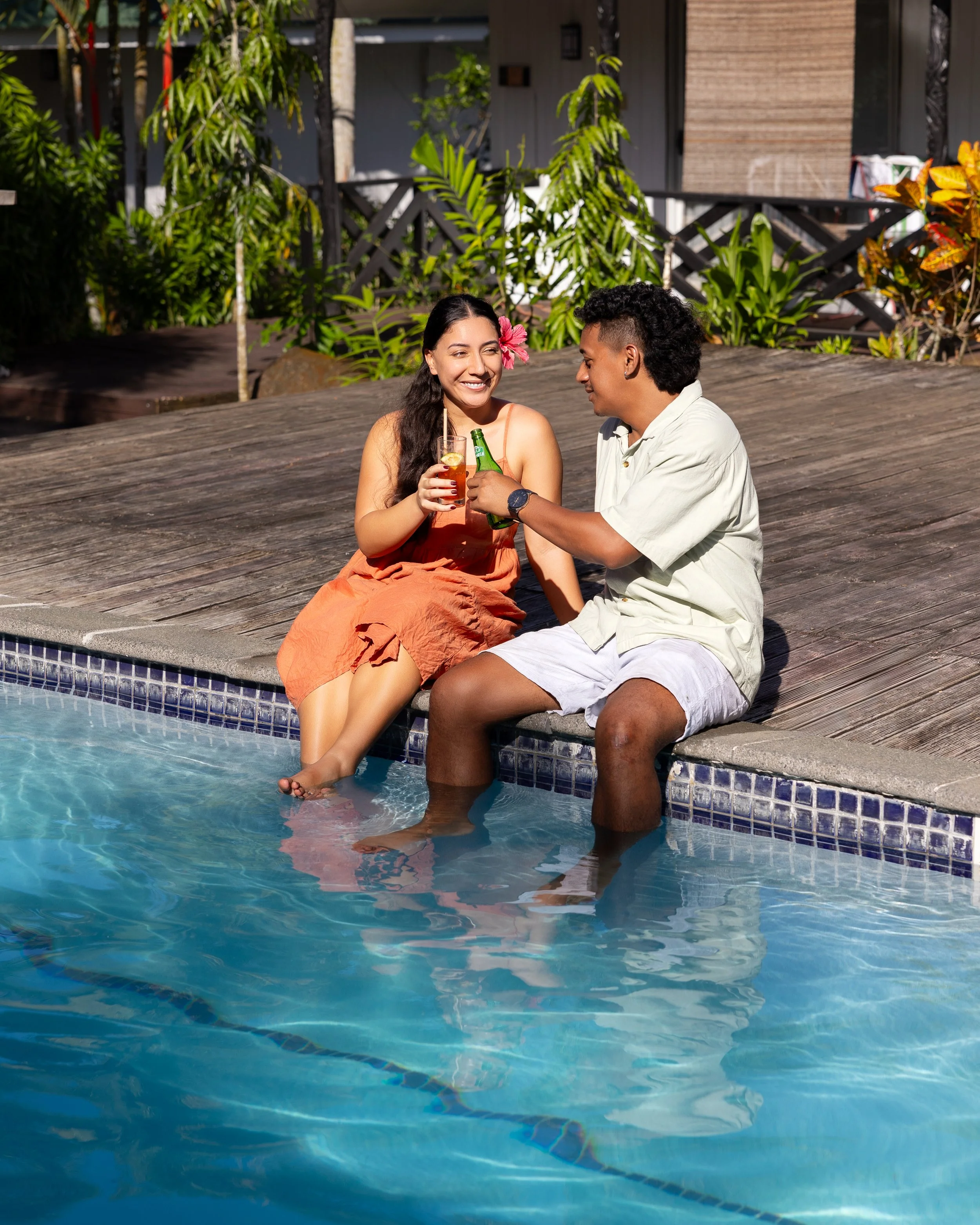 Couple cheering poolside while looking at each other smiling at Orator Hotel Samoa.