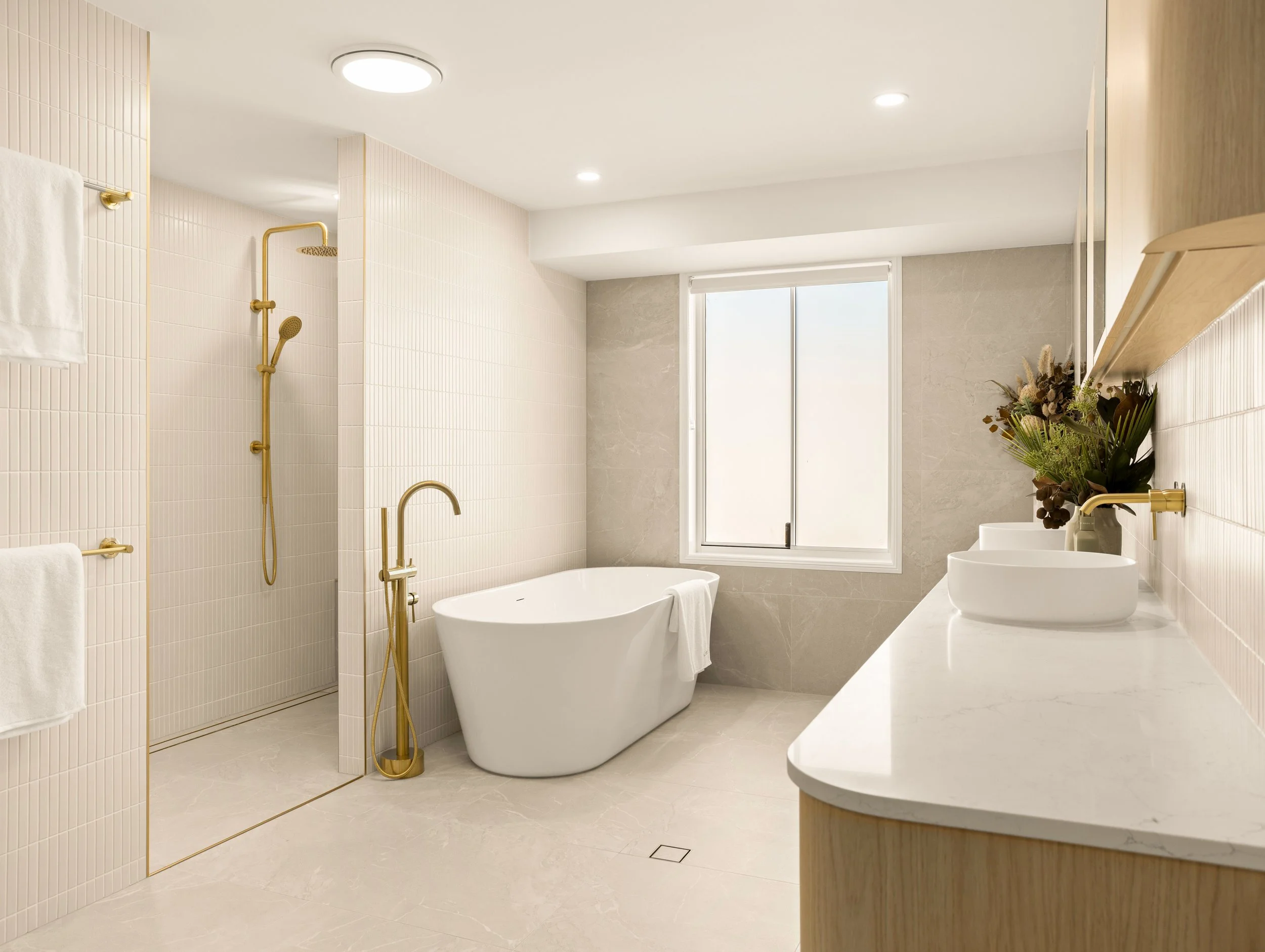 Modern bathroom with stand alone bathtub,stone benches and gold fitting in Brisbane.