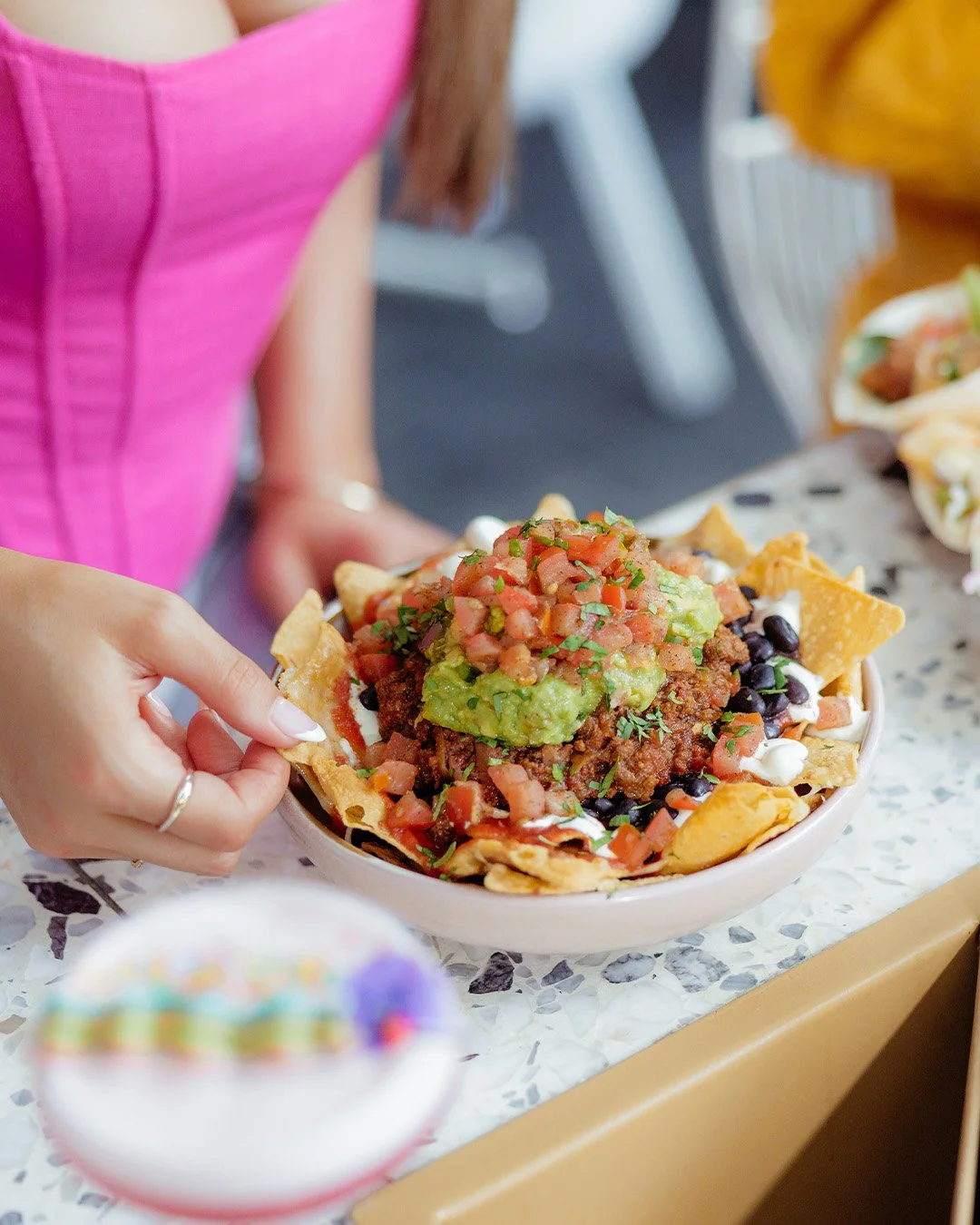 Young females hand picking up a corn chip in a narcho meal at Everton Park Plaza.