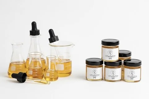 Various glass laboratory bottles and jars filled with yellow liquid, some with black lids, arranged on a white background.