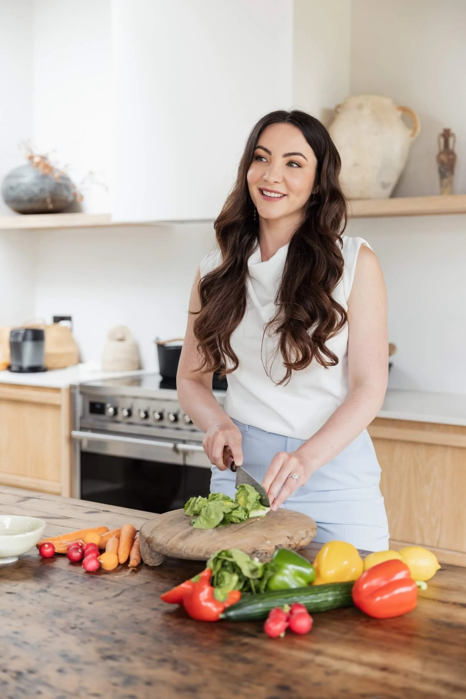 Nutritionist stands in a kitchen cutting up fresh fruit and vegetables