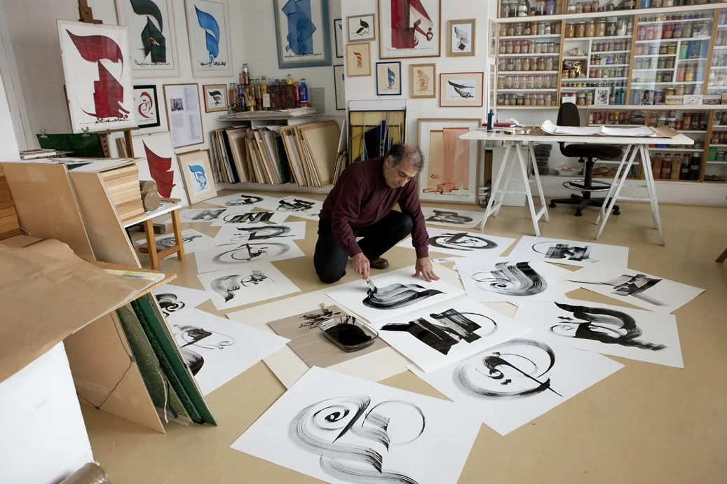   Hassan Massoudy in his studio, sheets of brushwork spread across the floor.  