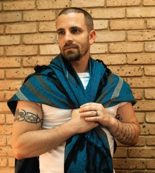Man with a Hebrew tattoo wearing a tallit, illustrating the essay on Rabbi Marshal Klaven's thesis, "The Tattoo That Wasn't Supposed to Exist"