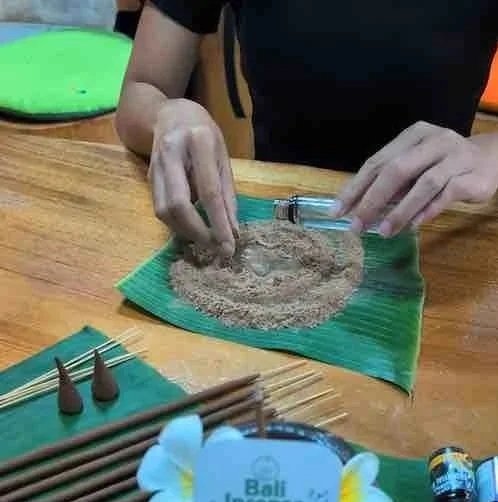 Person injecting a piece of fried chicken with a syringe on a green paper towel on a wooden table.