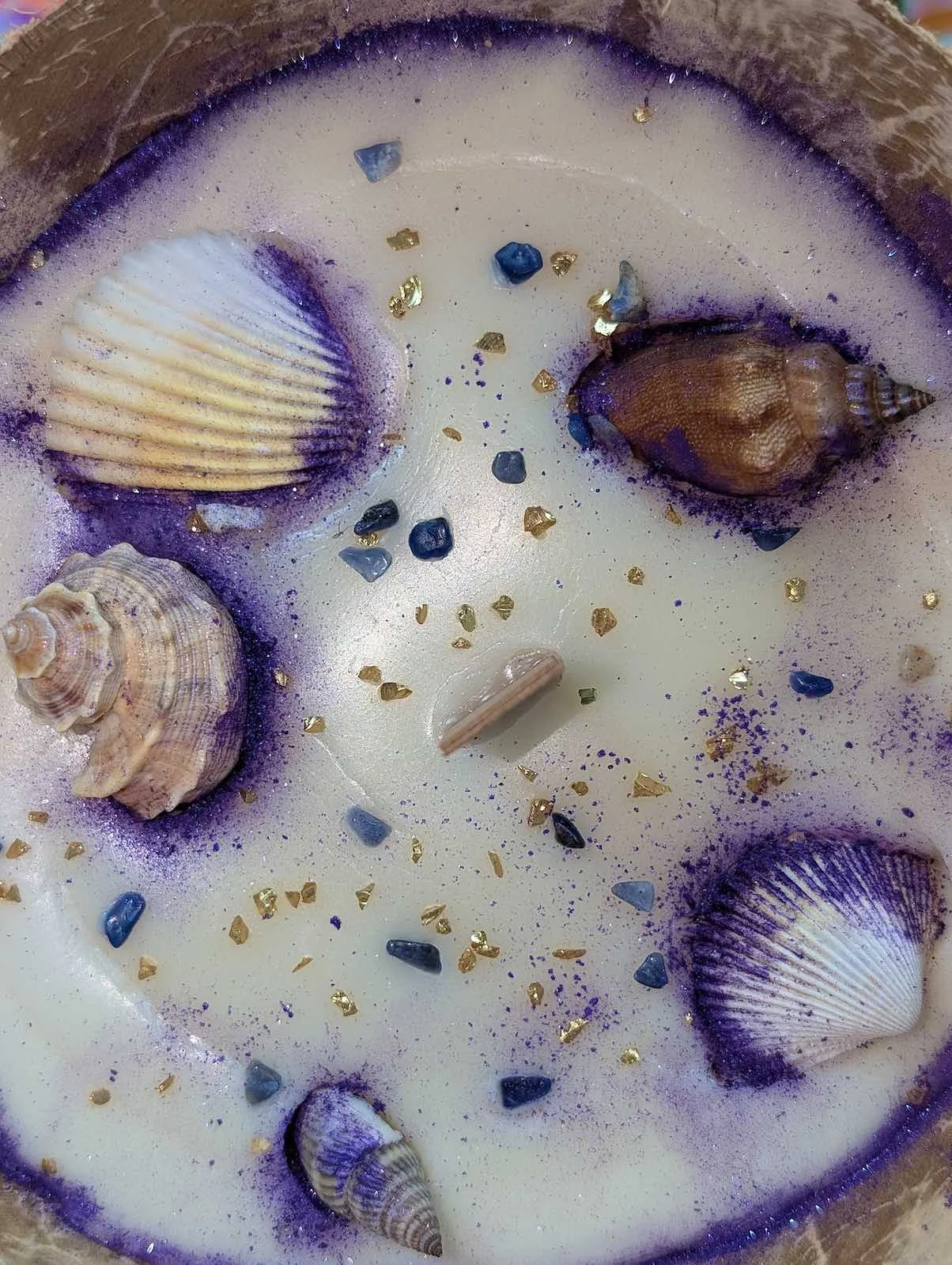 Decorative seashells and small stones on a white surface with purple and gold accents.