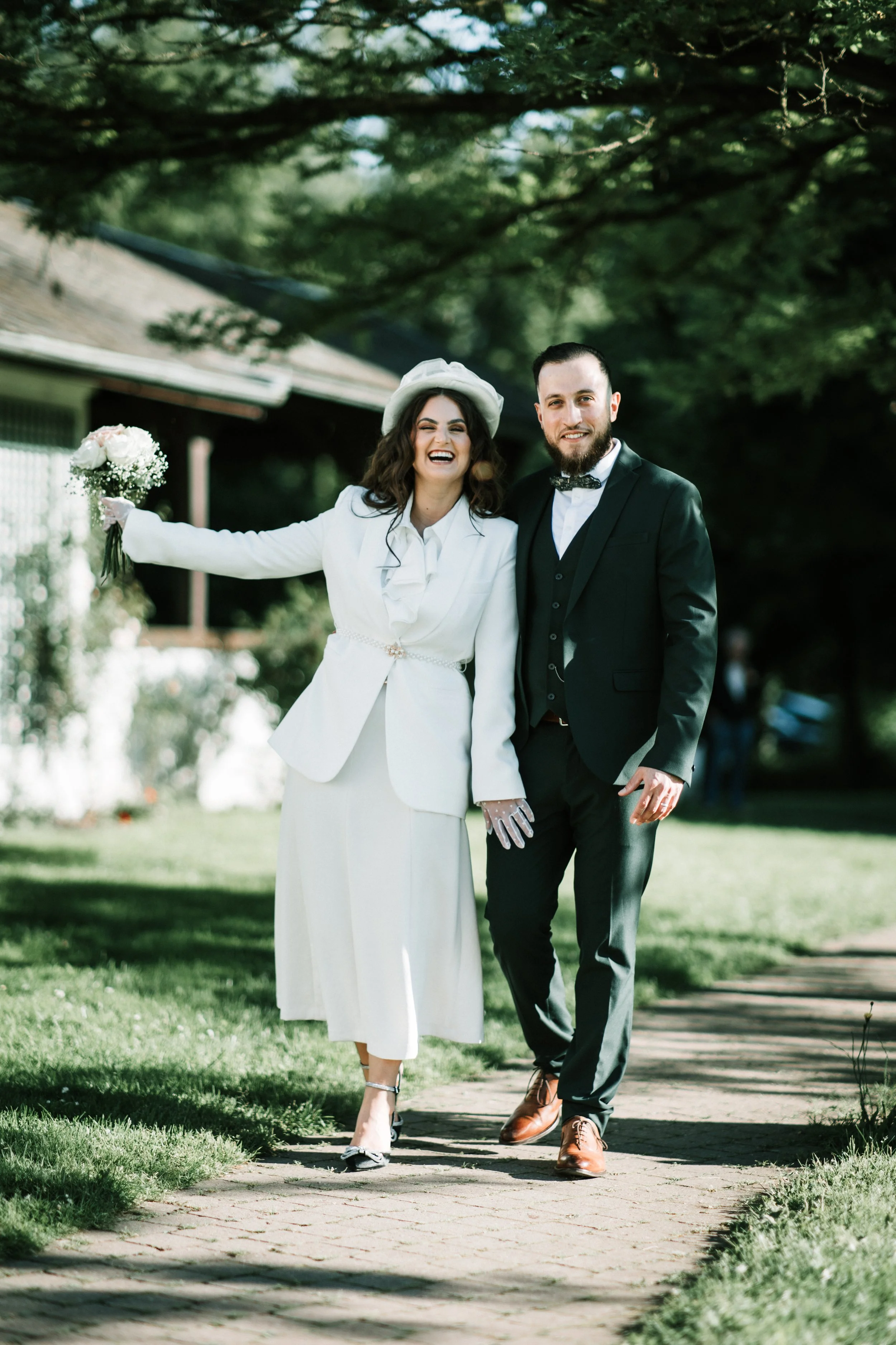jeunes mariés qui marchent main dans la main et sourient en regardant le photographe durant leurs shooting extérieur après la cérémonie de mariage à Strasbourg, jardin de Pourtales