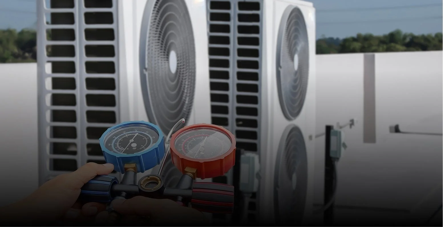 Technicien tenant un ensemble de jauges de collecteur mesurant la pression du réfrigérant sur une unité de climatisation HVAC.