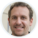 Portrait en gros plan d'un homme souriant aux cheveux bruns courts et à la barbe.