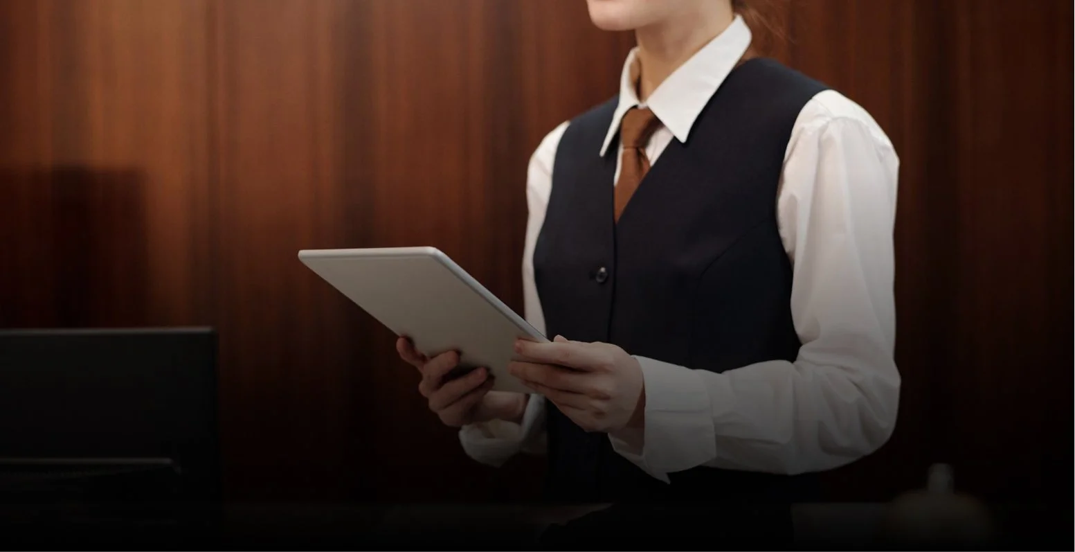Une personne en tenue professionnelle tenant une tablette dans un bureau.